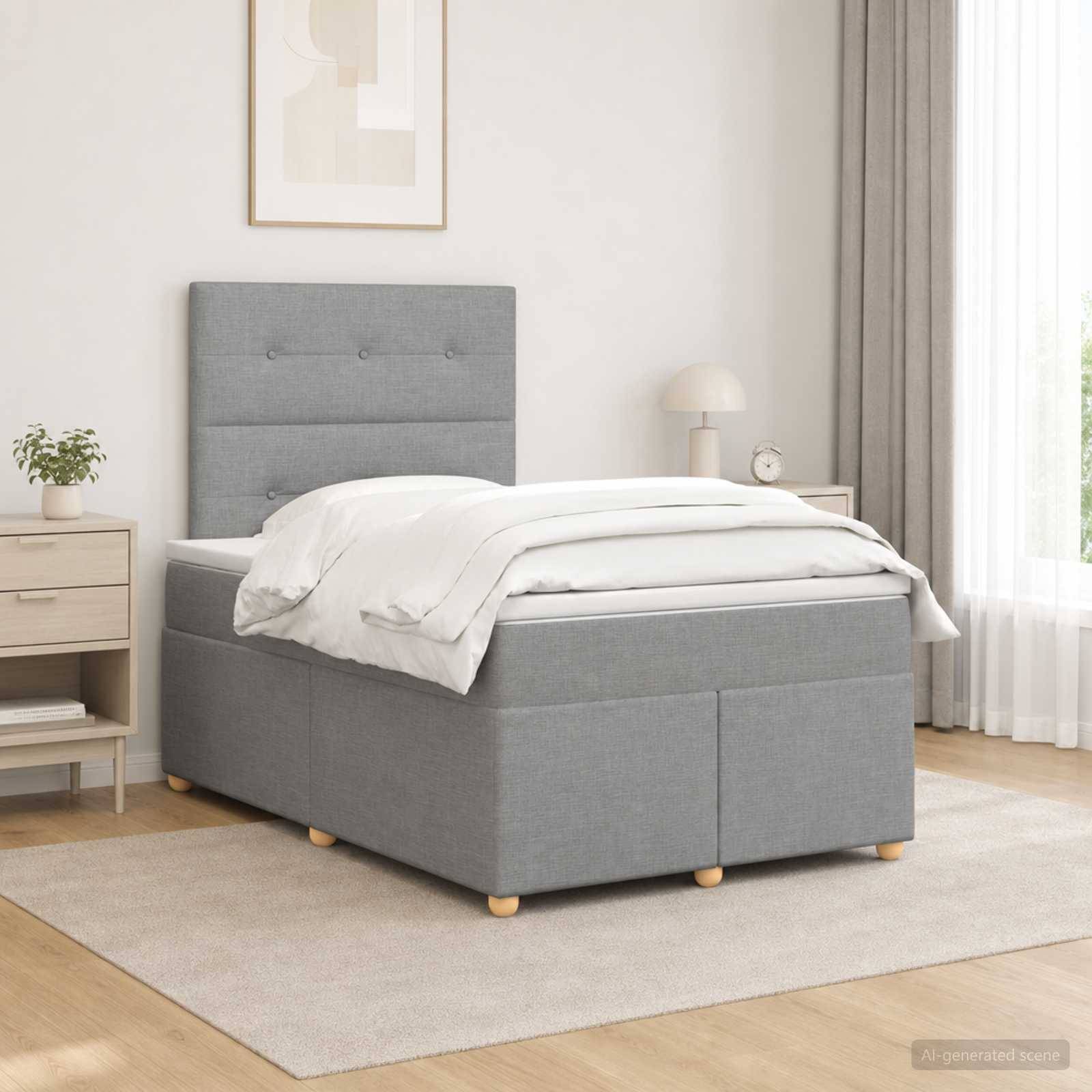 Graues gepolstertes Einzelbett mit weißer Bettwäsche in einem hellen, minimalistischen Schlafzimmer neben einem Nachttisch, einer Lampe und Fenstervorhängen.