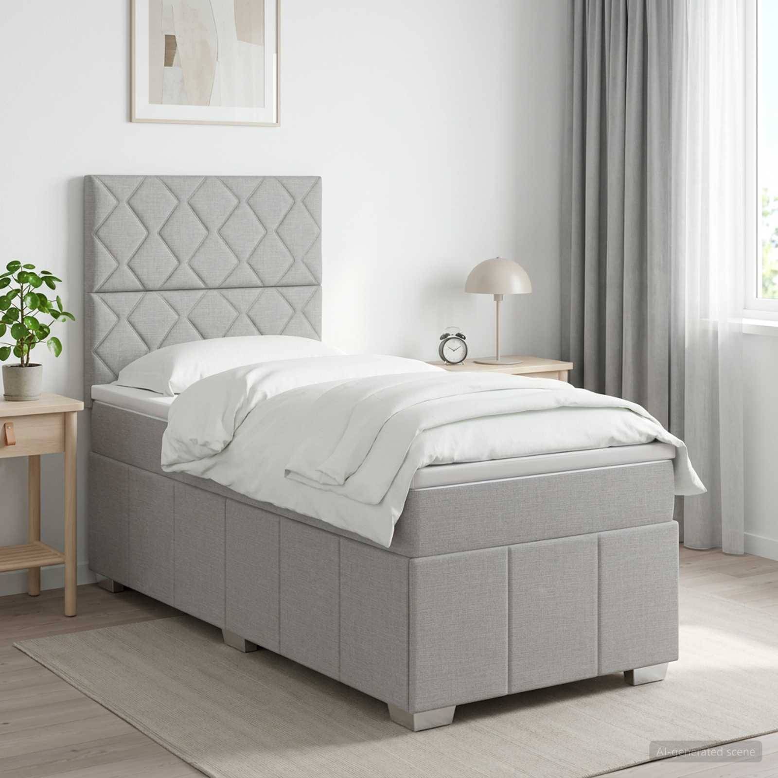 Grau gepolstertes Einzelbett mit diamantgestepptem Kopfteil, weißer Bettwäsche und passendem Stauraumbasis in einem hellen, minimalistischen Schlafzimmer.
