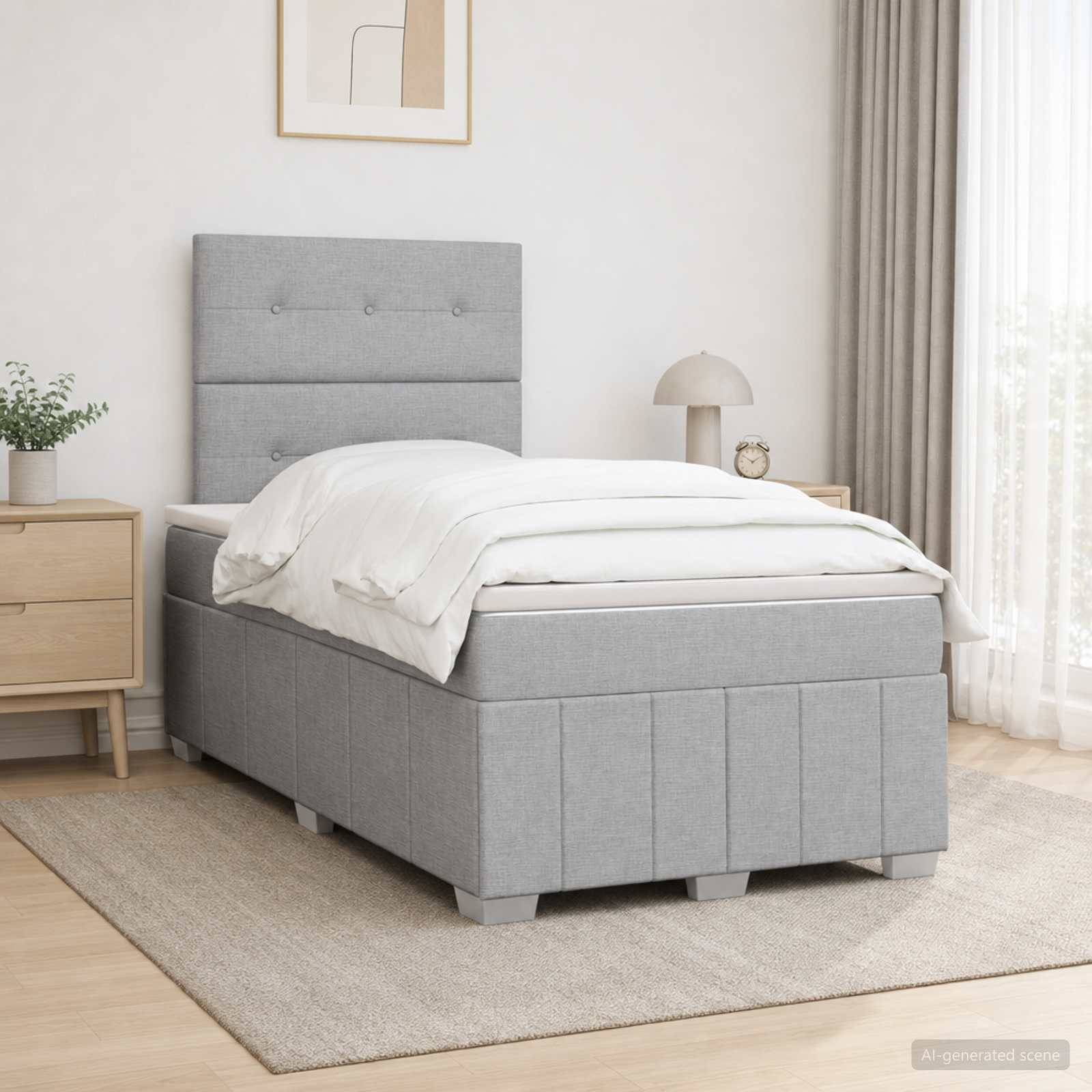 Ein grau gepolstertes Bett mit passendem Kopfteil und Stauraumbasis in einem hellen minimalistischen Schlafzimmer, ausgestattet mit weißer Bettwäsche.