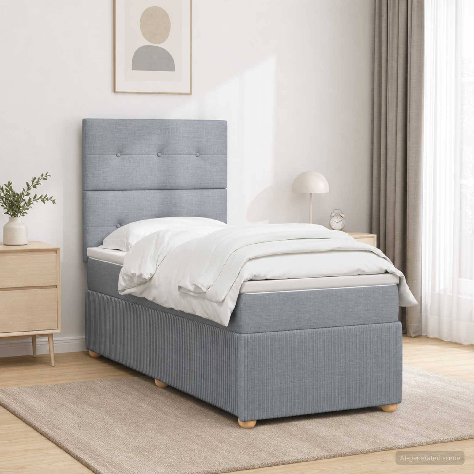 Einzelbett mit grau gepolstertem Kopfteil und Stauraumbasis in einem hellen, minimalistischen Schlafzimmer mit weißer Bettwäsche und Holzmöbeln.