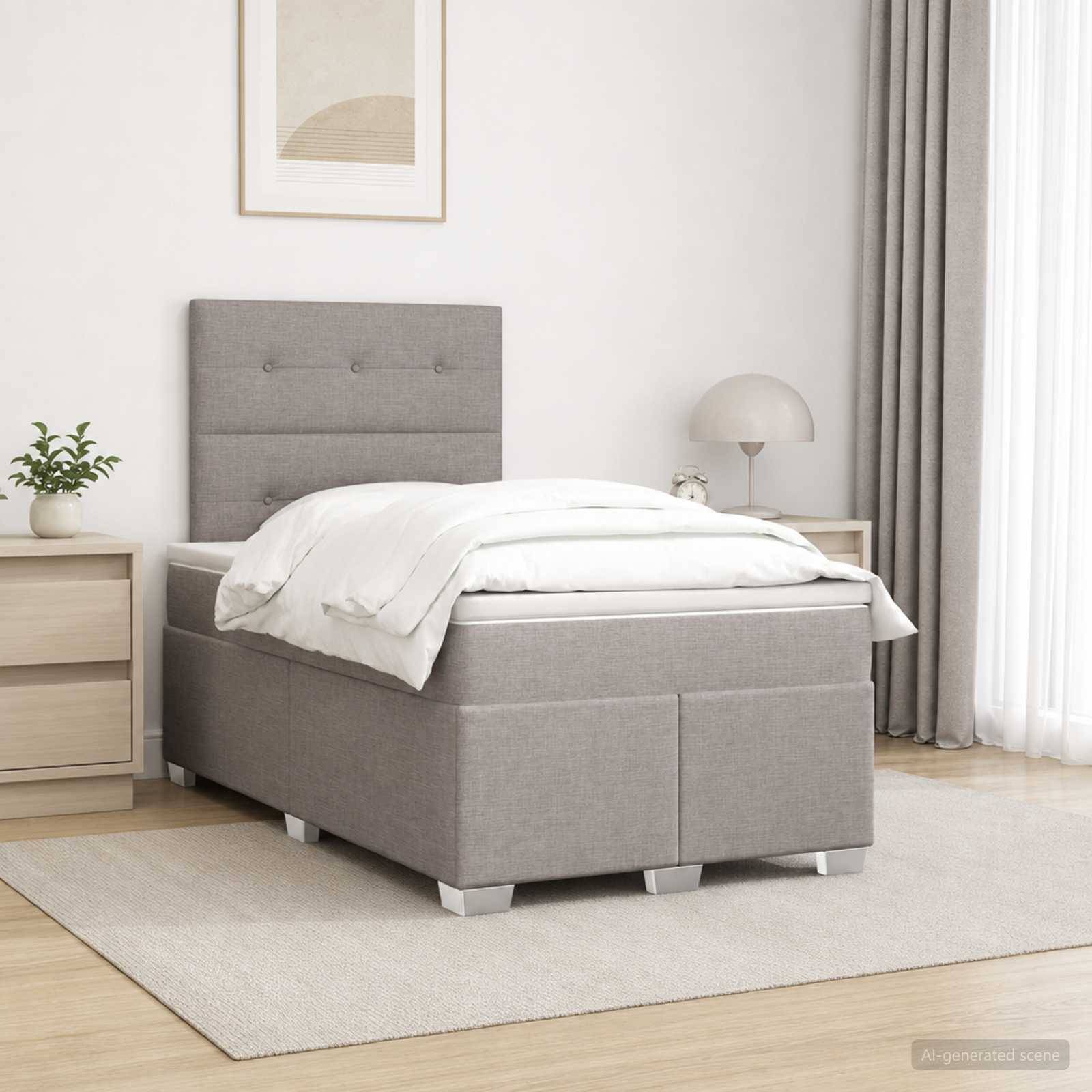 Ein minimalistisches Schlafzimmer mit einem grau gepolsterten Bett, weißer Bettwäsche, Nachttisch mit Pflanze und Lampe sowie Gardinen bei einem hellen Fenster.