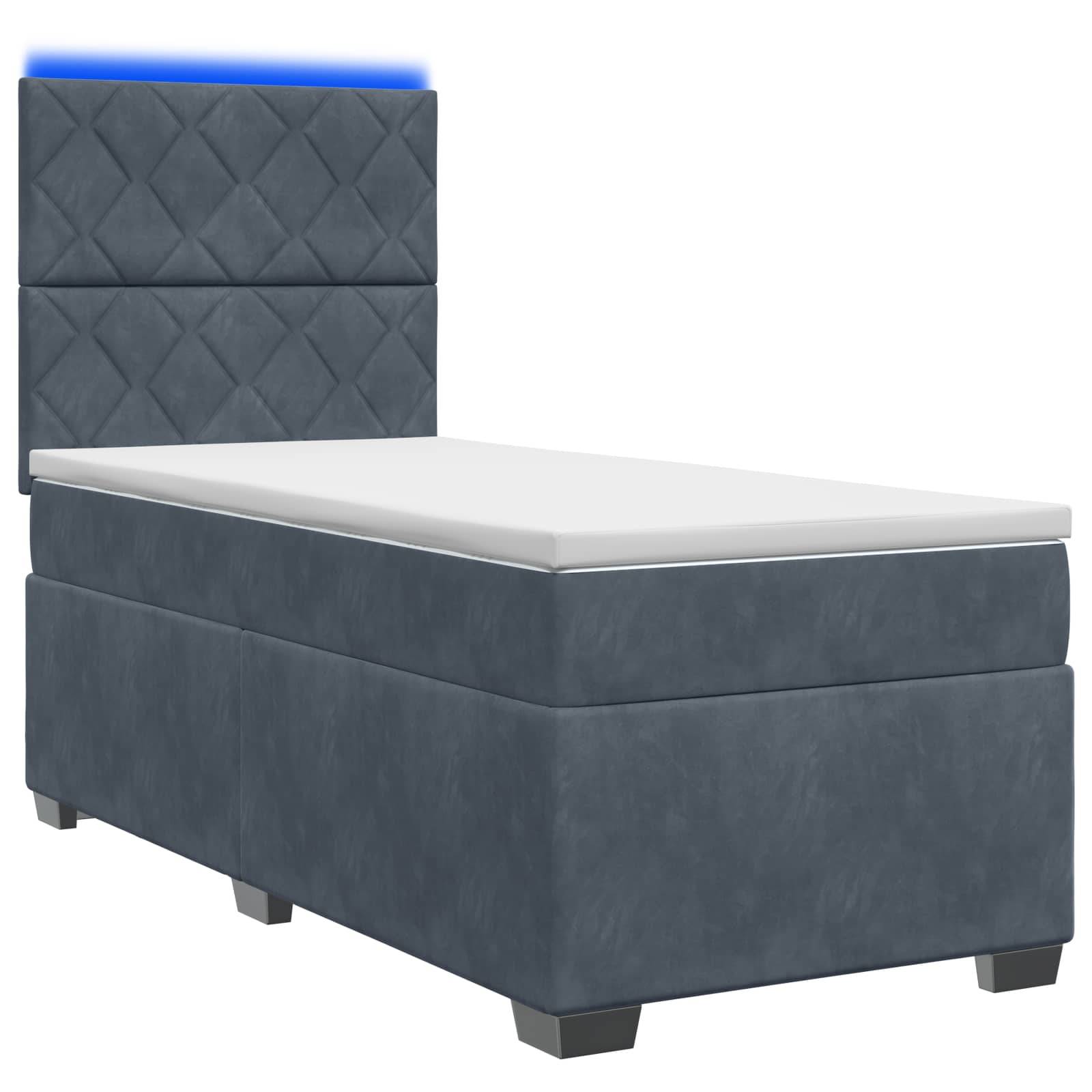 Blaugepolstertes Einzelbett mit gestepptem Kopfteil und weißer Matratze auf neutralem Hintergrund.