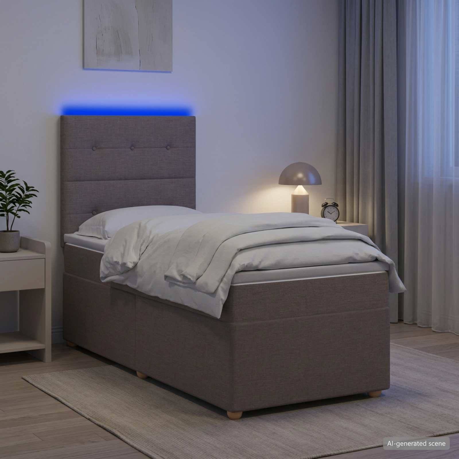 Ein ordentlich gemachtes Einzelbett mit grauem gepolstertem Kopfteil, das in Blau leuchtet, neben einem Nachttisch und einer Lampe in einem modernen Schlafzimmer.