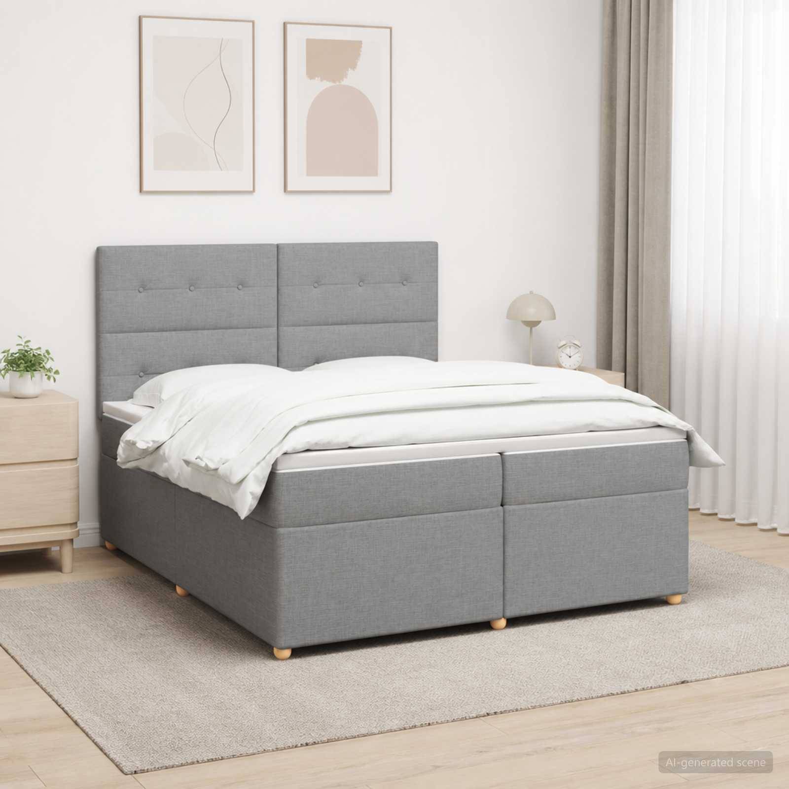 Modernes grau gepolstertes Bett mit gestepptem Kopfteil und weißer Bettwäsche in einem hellen, minimalistischen Schlafzimmer, gezeigt auf einem hellen Teppich mit Nachttisch und gerahmter Wandkunst.