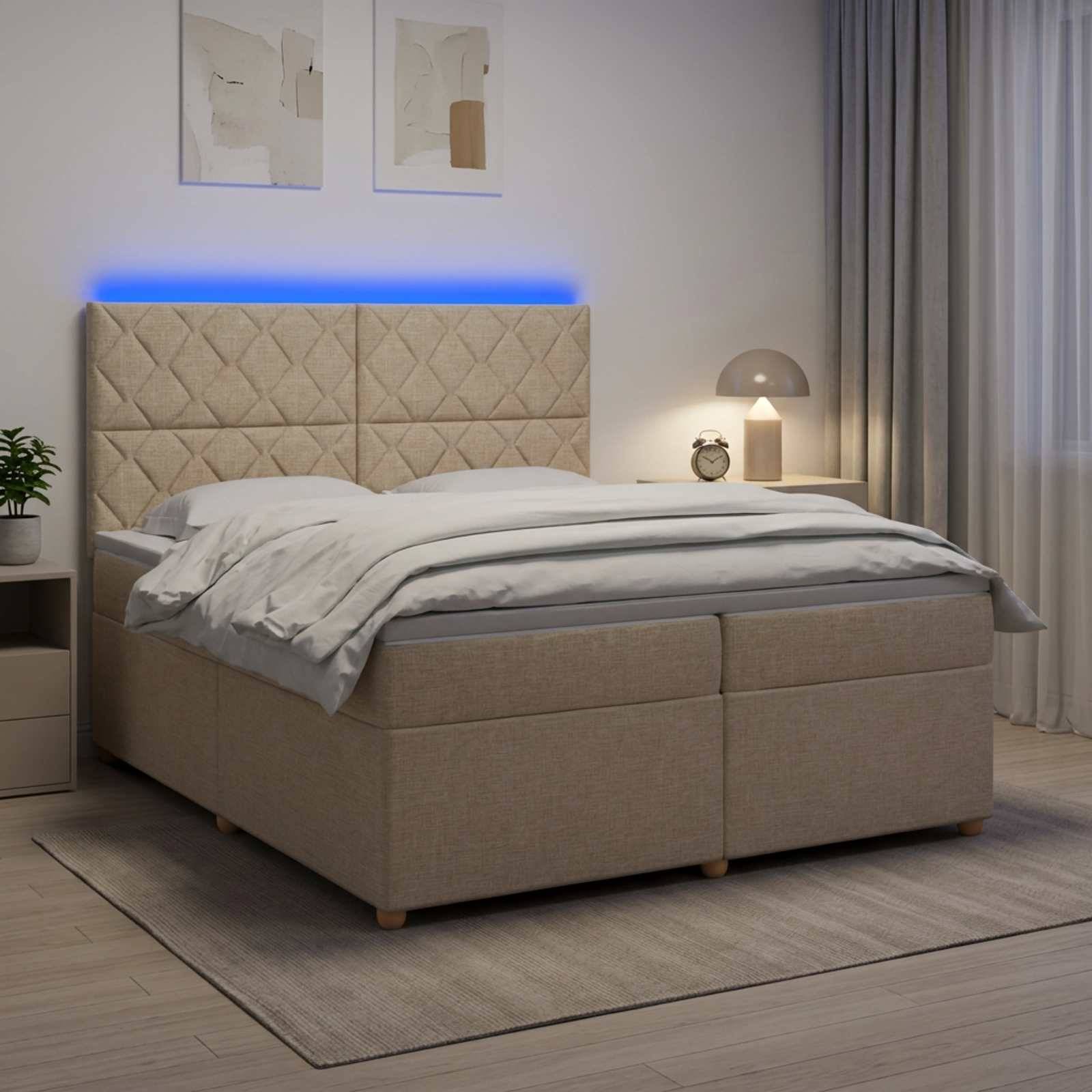 Modernes beiges Polsterbett mit gestepptem Kopfteil und blauer LED-Hintergrundbeleuchtung in einem sanft beleuchteten Schlafzimmer, mit grauer Bettwäsche, Nachttisch, Lampe und Vorhängen.