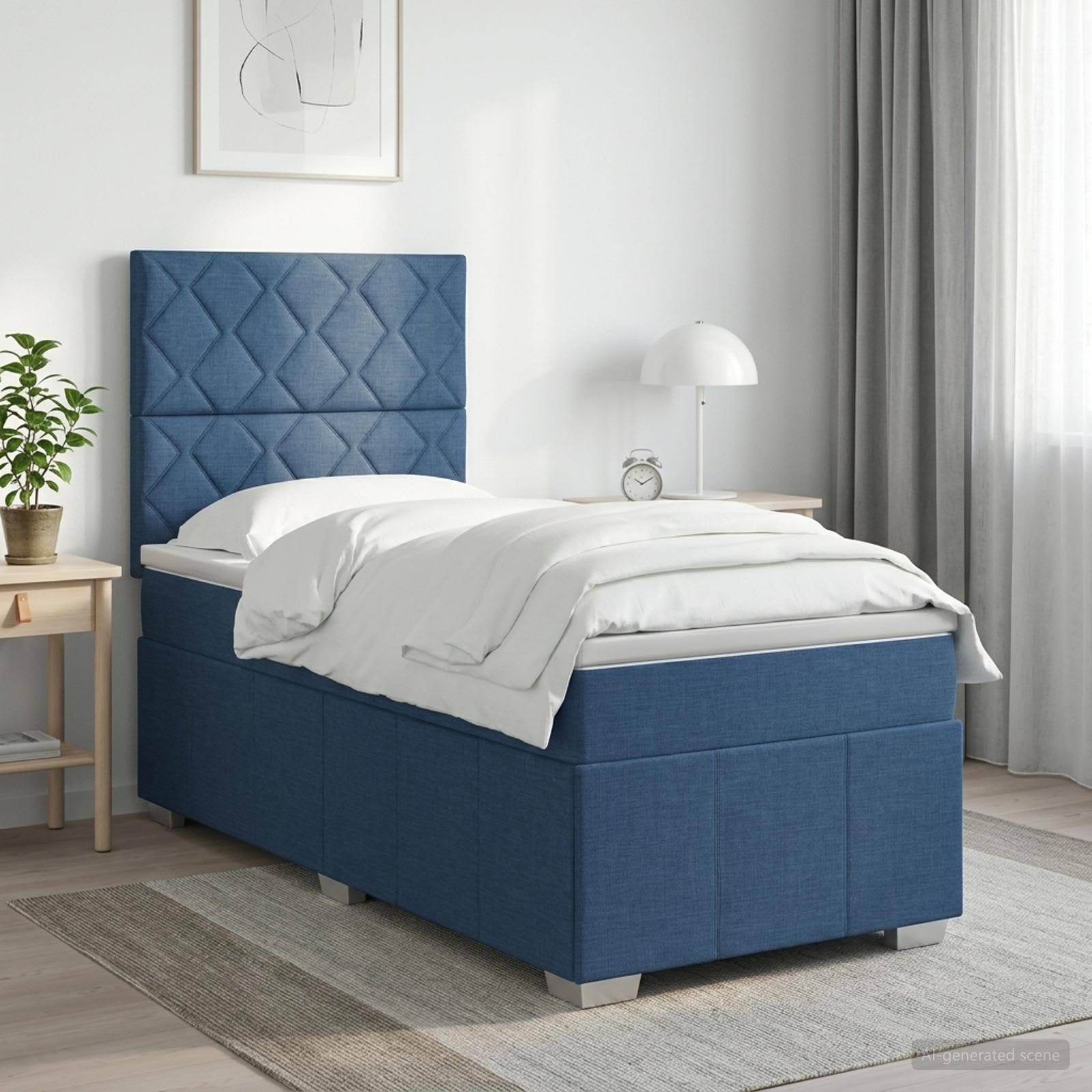 Blaugepolstertes Einzelbett mit gestepptem Kopfteil in einem hellen Schlafzimmer, bezogen mit weißer Bettwäsche neben einem Nachttisch, einer Lampe und einer Pflanze.