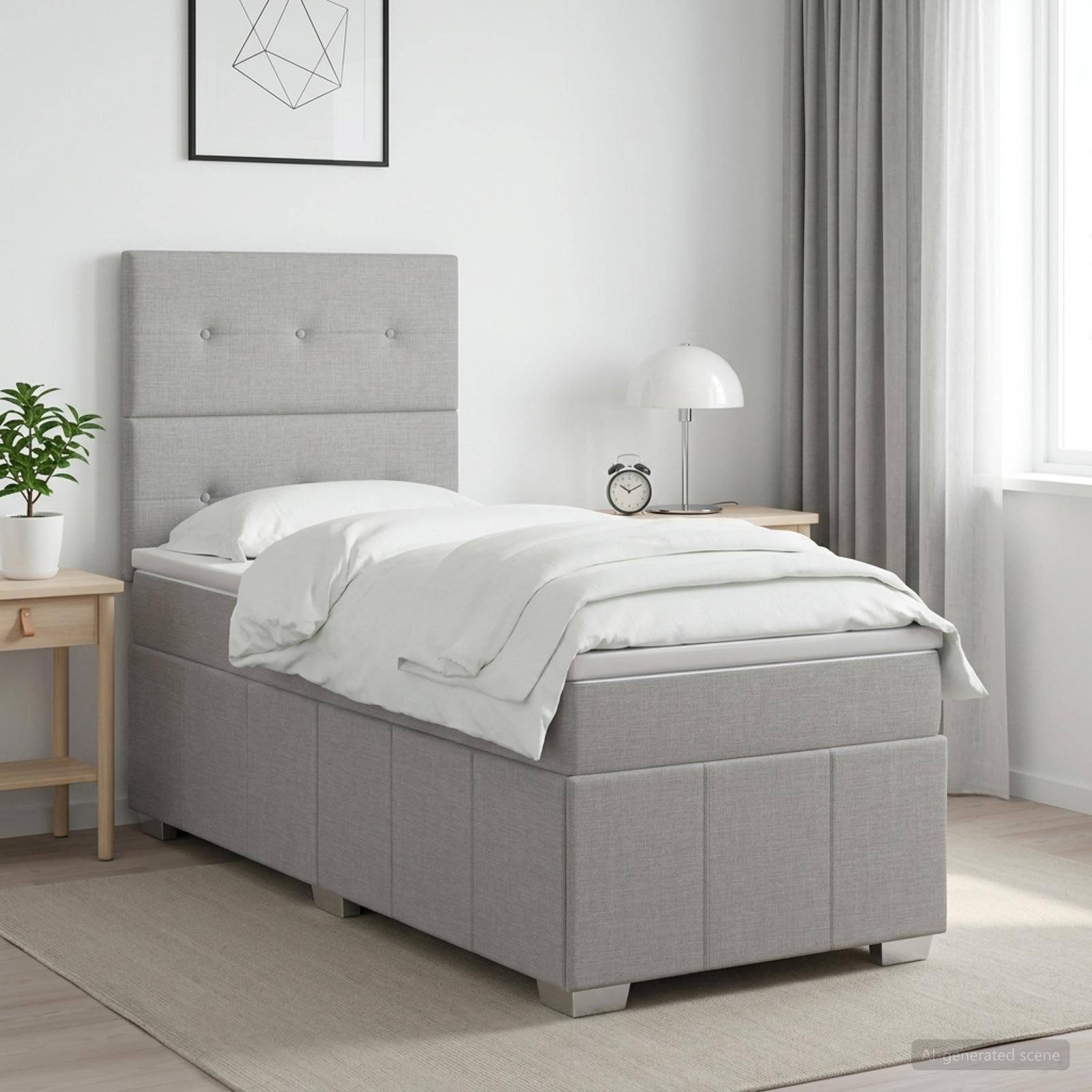 Minimalistisches Schlafzimmer mit einem grau gepolsterten Einzelbett, weißer Bettwäsche, Nachttisch, Lampe, Pflanze und gerahmter Wandkunst im weichen Tageslicht.