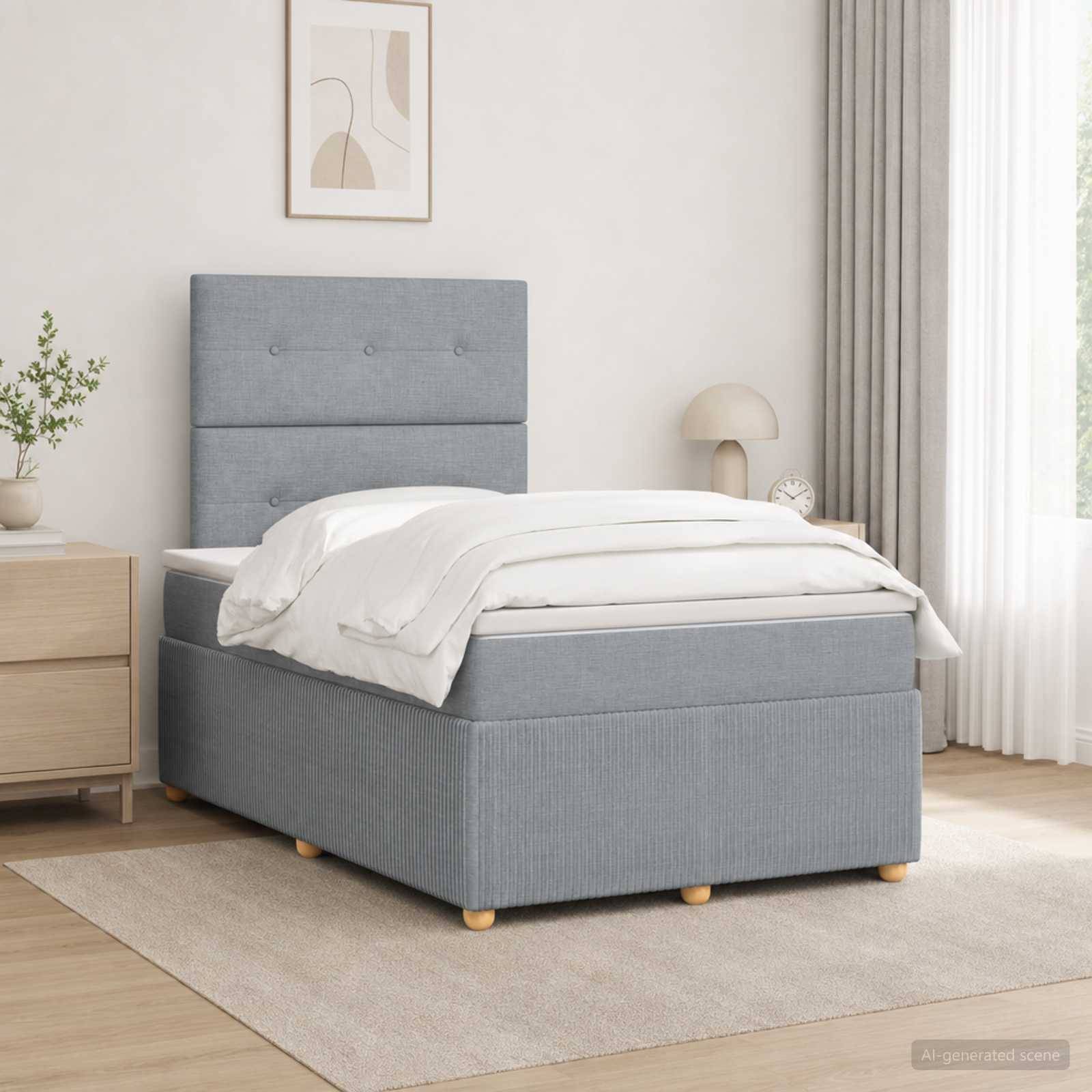 Ein ordentlich gemachtes grau gepolstertes Bett mit weißer Bettwäsche in einem hellen, minimalistischen Schlafzimmer neben einem Holz-Nachttisch, einer Lampe und einem Fenster mit Vorhängen.