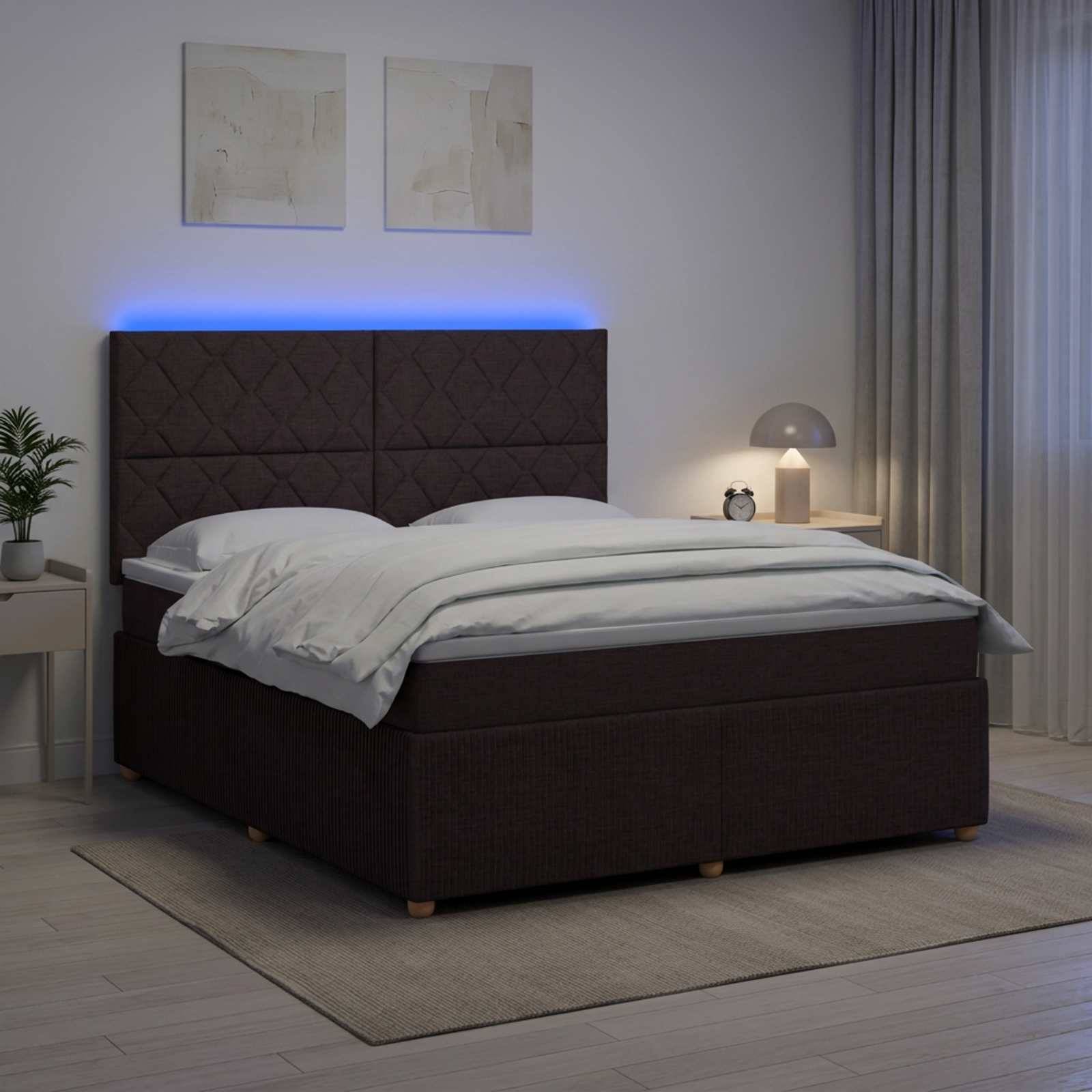 Modernes Schlafzimmer mit dunklem gepolstertem Bett, blau hinterleuchtetem Kopfende, weißer Bettwäsche, Nachttischlampe, Pflanze und neutraler Dekoration.