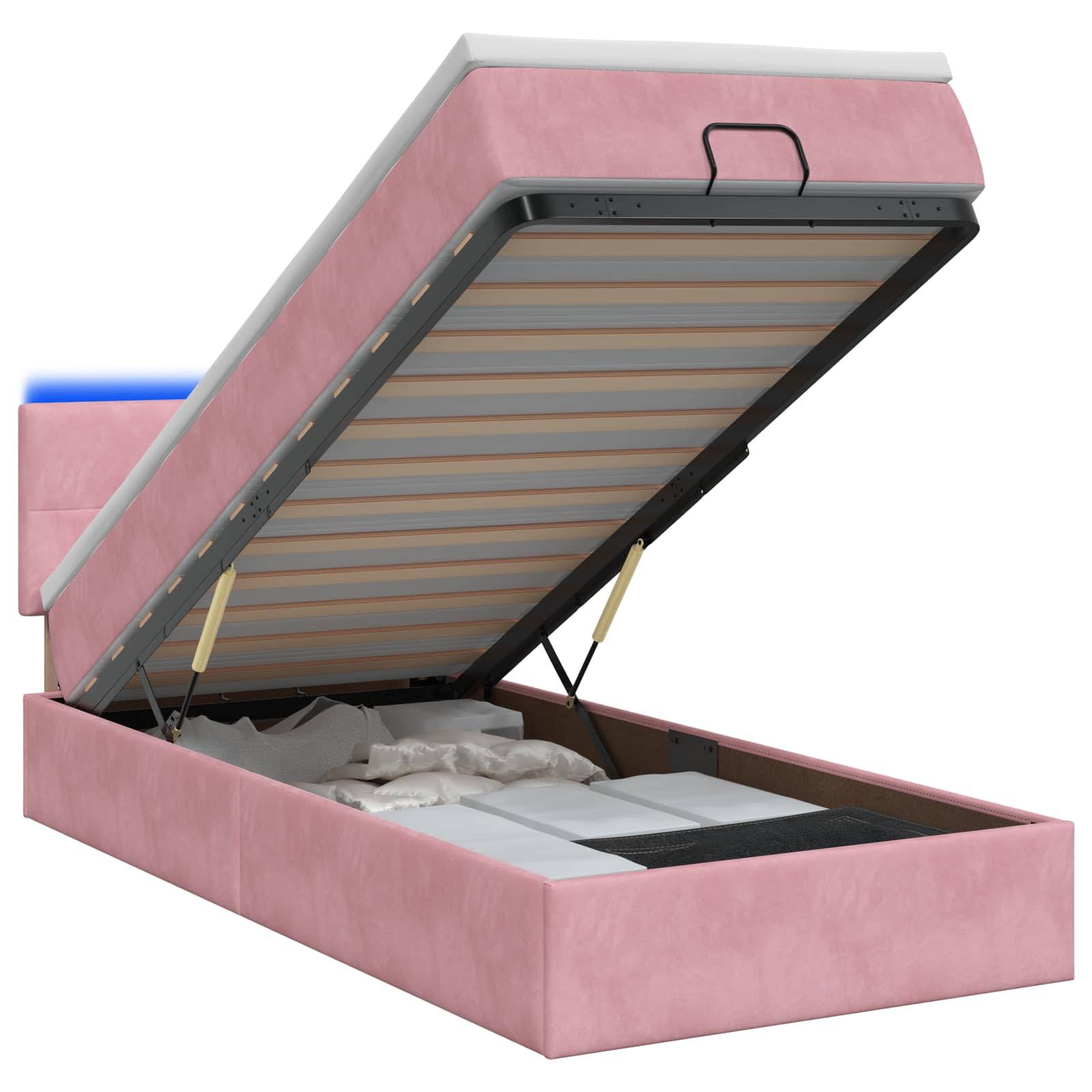 Rosa gepolstertes Speicherbett mit angehobener Matratze auf einer Scharnierbassis, die das Unter-Bett-Speicherfach offenlegt.