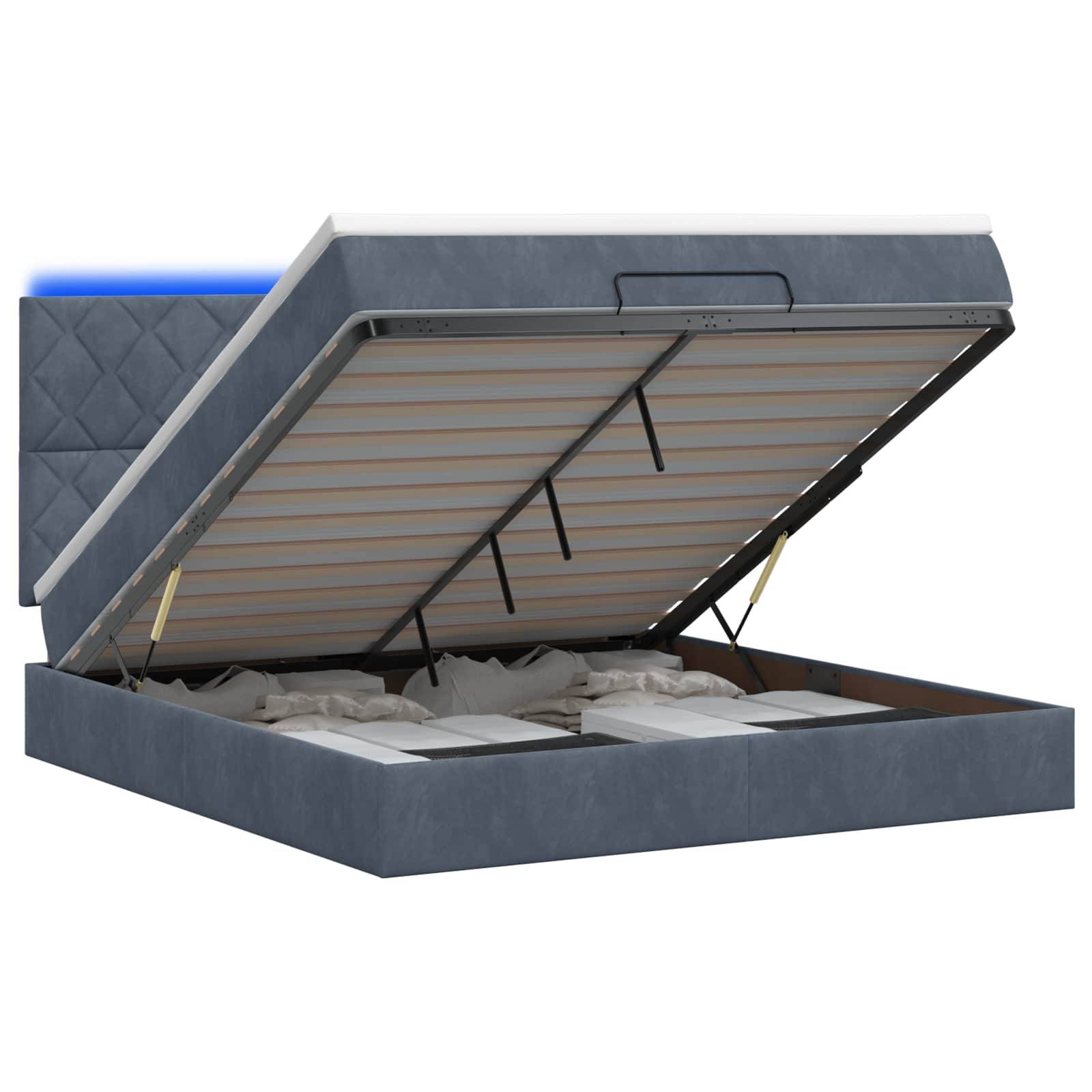 Blaugepolstertes Speicherbett mit geöffnetem Lattenrost, das das darunter liegende Stauraum-Fach offenbart.