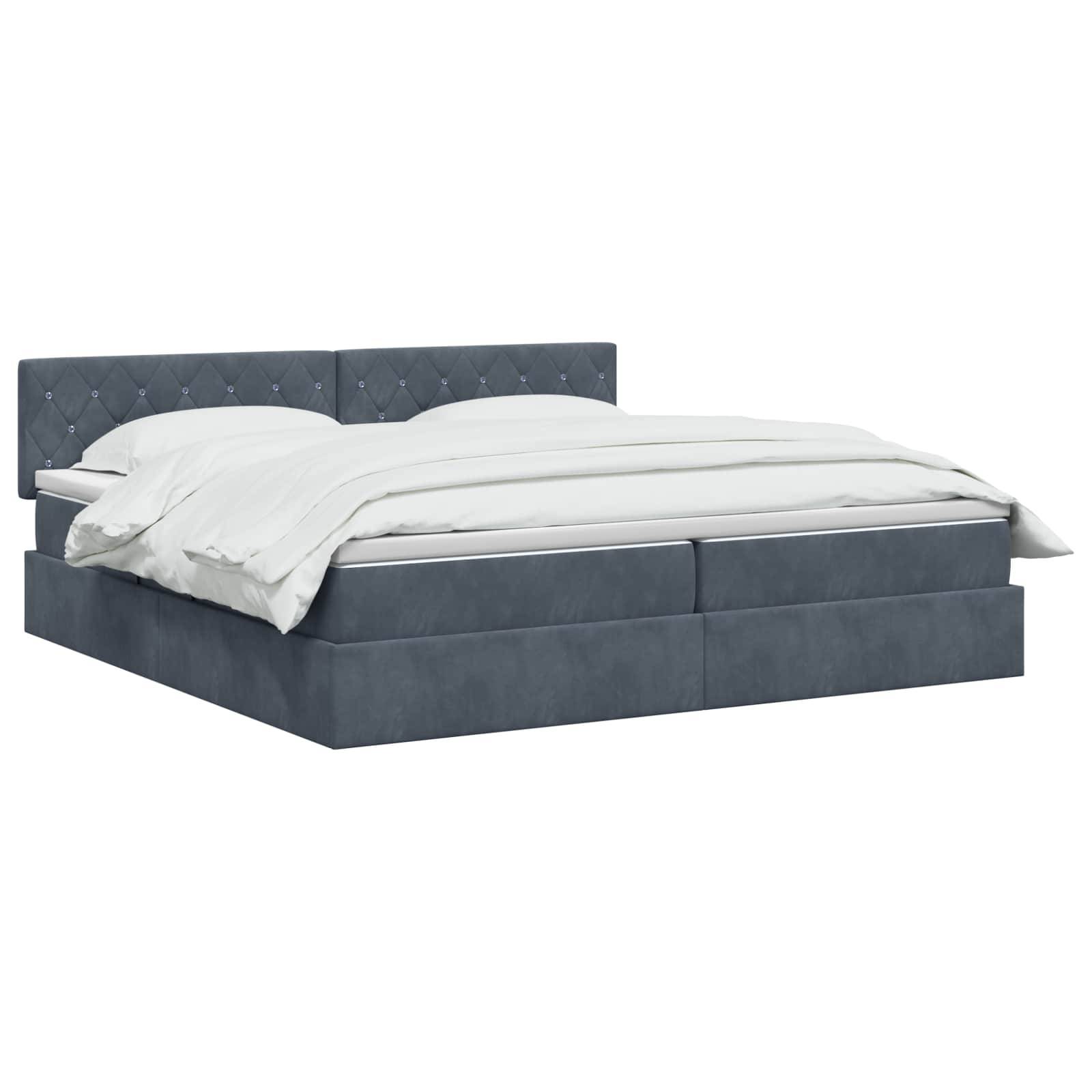 Bett mit blauem Polsterstoff, gestepptem Kopfteil und weißer Bettwäsche auf einfachem weißem Hintergrund.