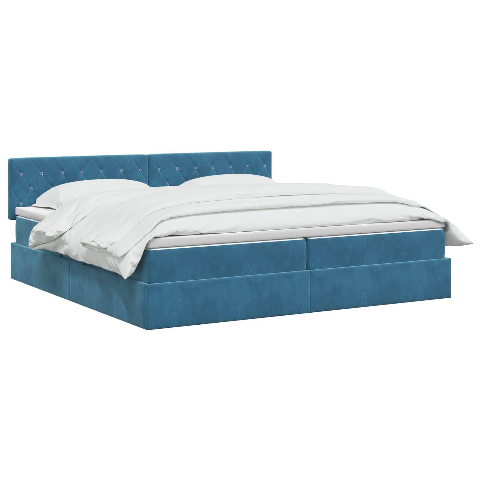 Bett mit blauem Polsterstoff, gestepptem Kopfteil und weißer Bettwäsche auf einfachem weißem Hintergrund.