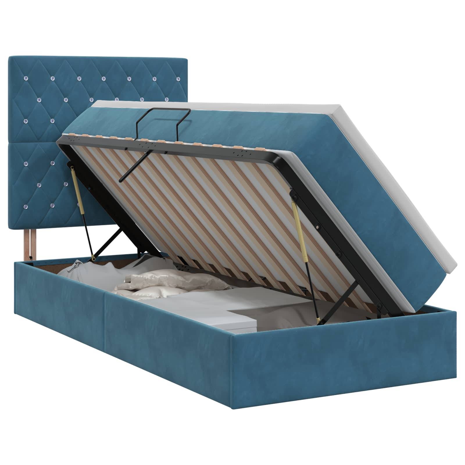 Blaues gepolstertes Speicherbett mit angehobenem Matratzen, die Lamellenbasis und das Unter-Bett-Fach zeigend; getuftetes Kopfteil dahinter sichtbar.