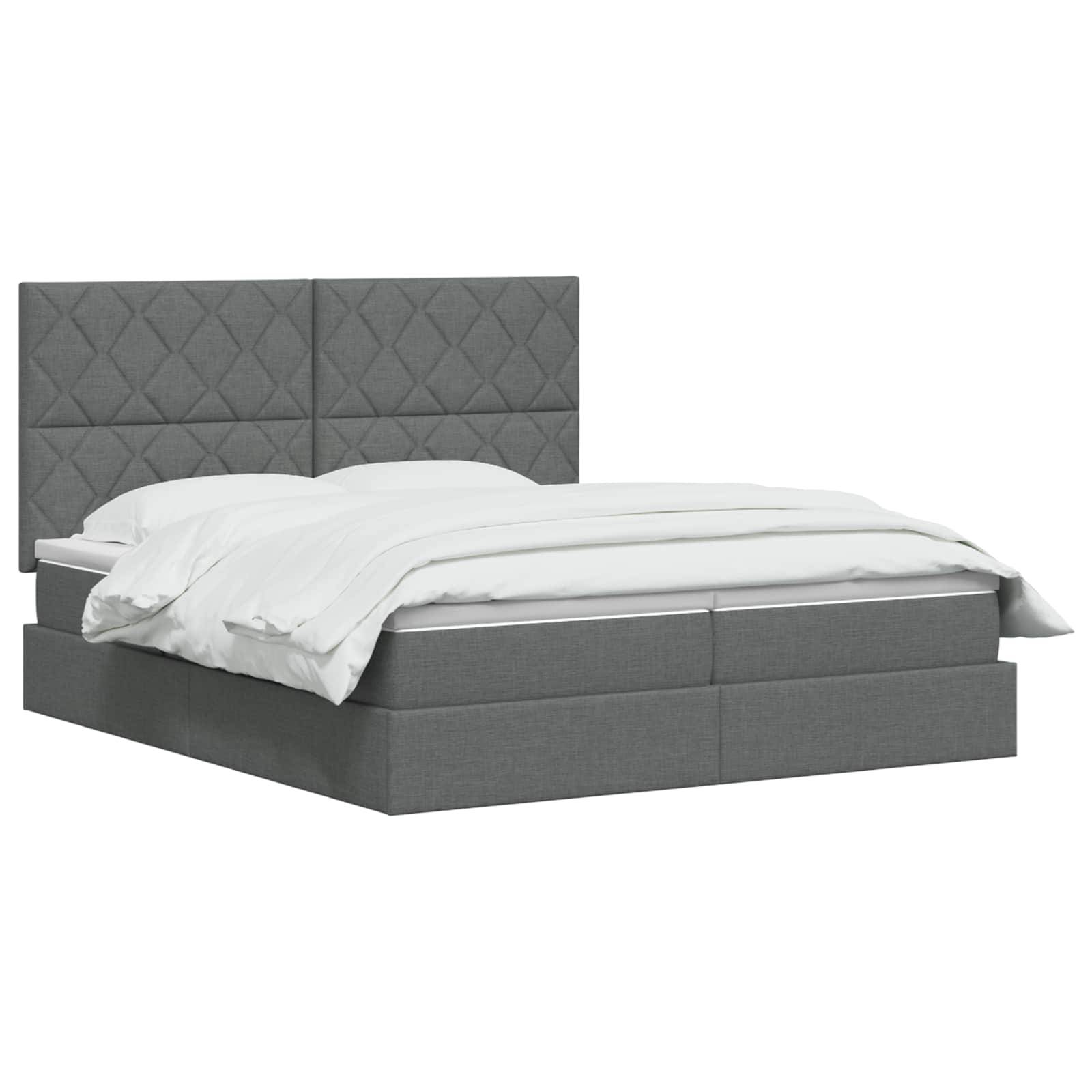 Grau gepolstertes Bett mit gestepptem Kopfteil und weißer Bettwäsche auf einem schlichten weißen Hintergrund.
