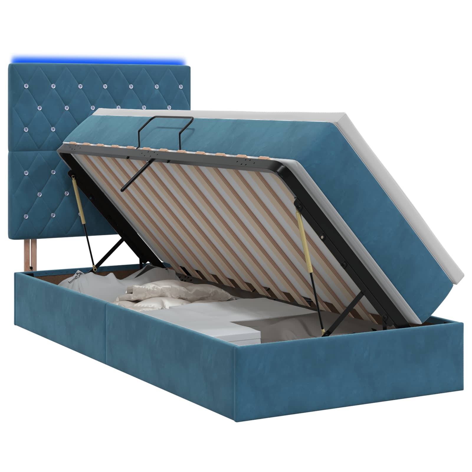 Blau gepolstertes Speicherbett mit gestepptem Kopfteil, geöffnet dargestellt, um die angehobene Matratzenunterstützung und den Stauraum unter dem Bett zu zeigen.