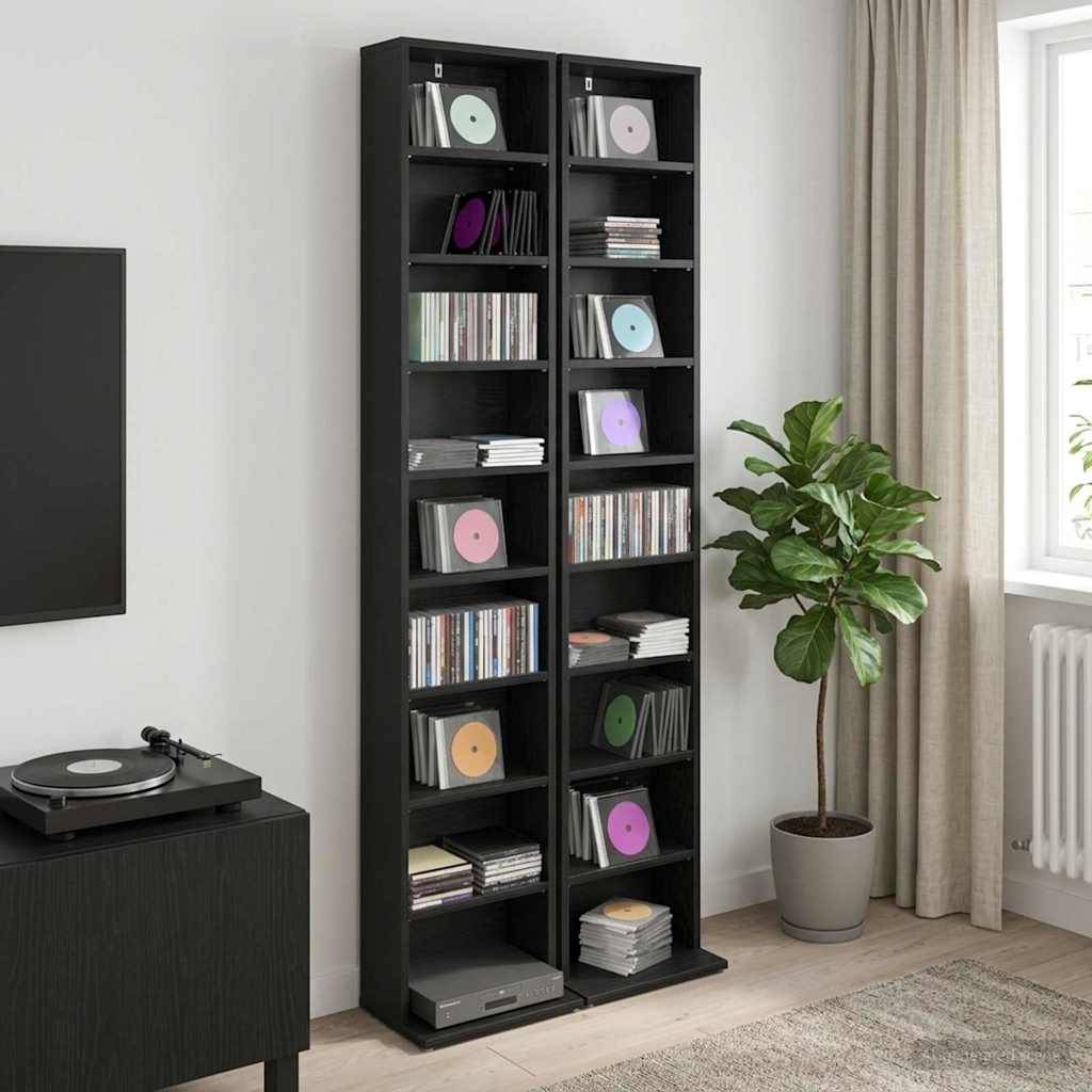 Eine Wohnzimmerecke mit hohem schwarzem Regal voller Schallplatten und Bücher, einem Plattenspieler-Schrank, einer Topfpflanze und einem Fenster mit Vorhängen.