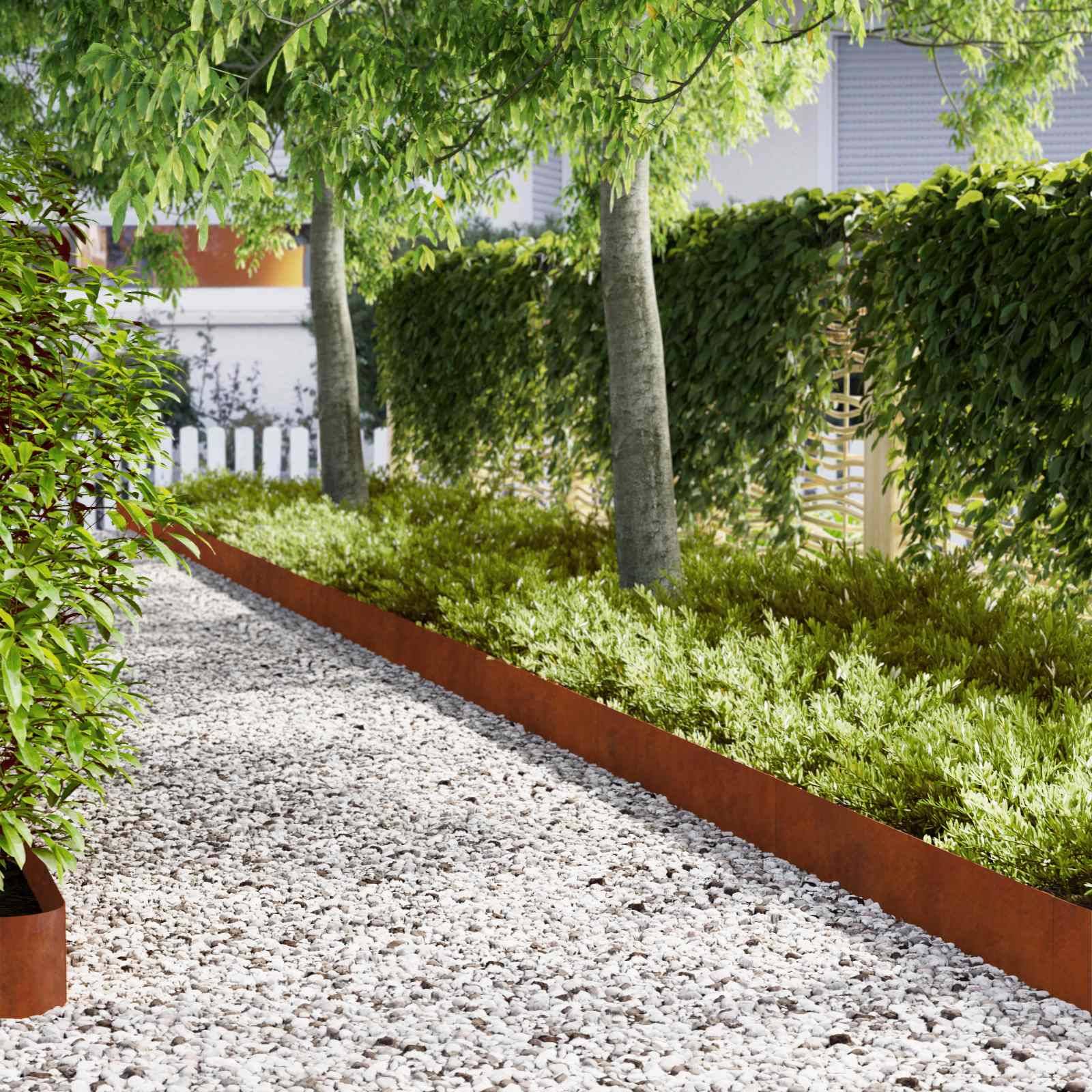 Ein gestalteter Gartenpfad aus weißem Kies, gesäumt von rostfarbigen Einfassungen, mit gepflegten Sträuchern und Bäumen neben einem Gebäude.
