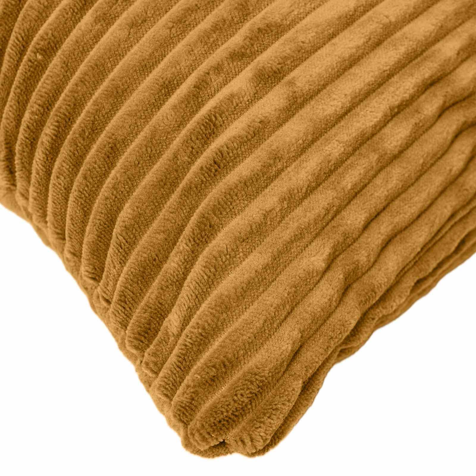 Nahaufnahme einer beige gerippten Kordsamtkissencke vor weißem Hintergrund.