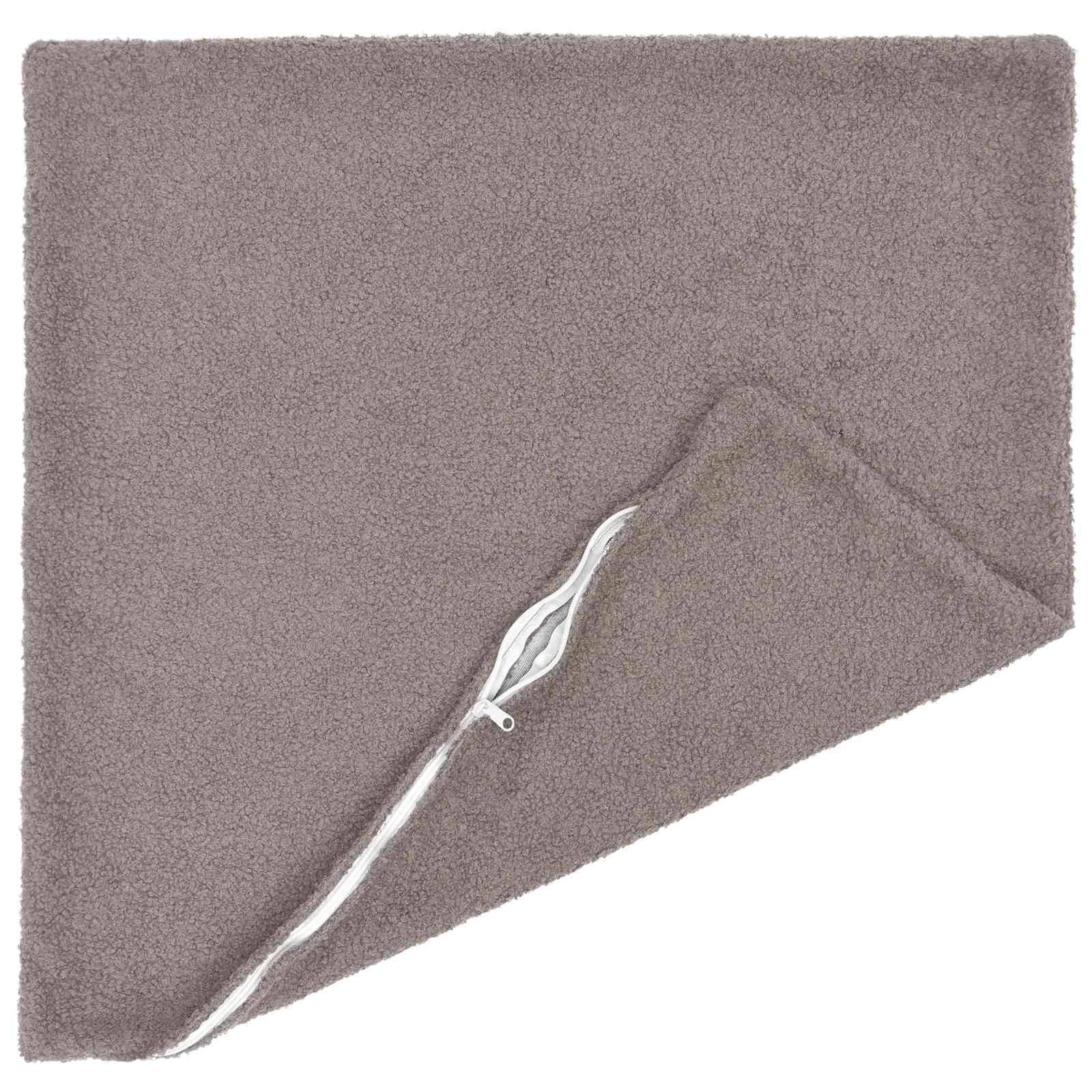 Taupefarbener rechteckiger Teppich mit einer zurückgeklappten Ecke, die eine weiße Unterseite/Kantenverzierung zeigt.