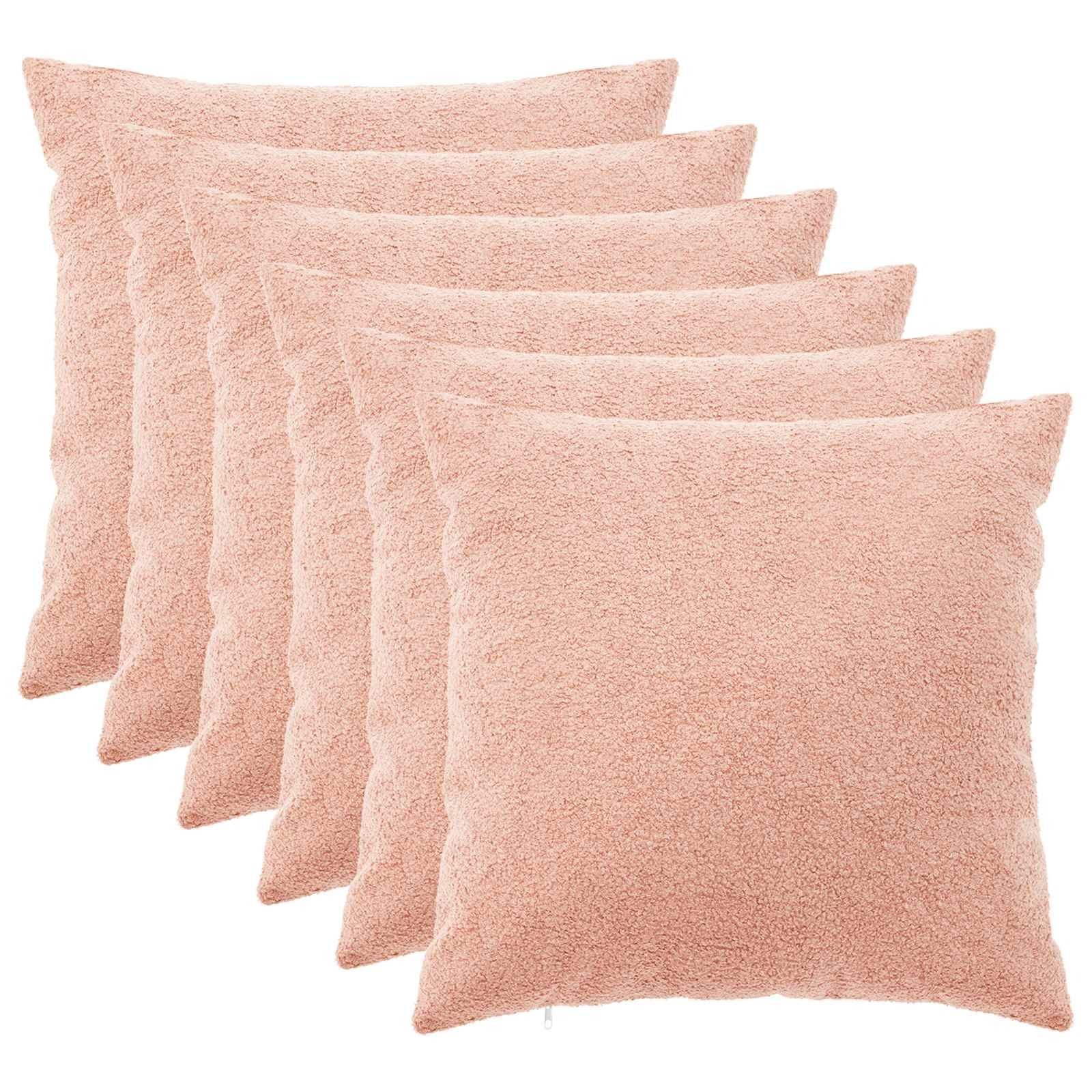 Stapel von sechs rosa strukturierten Wurfkissen auf weißem Hintergrund.