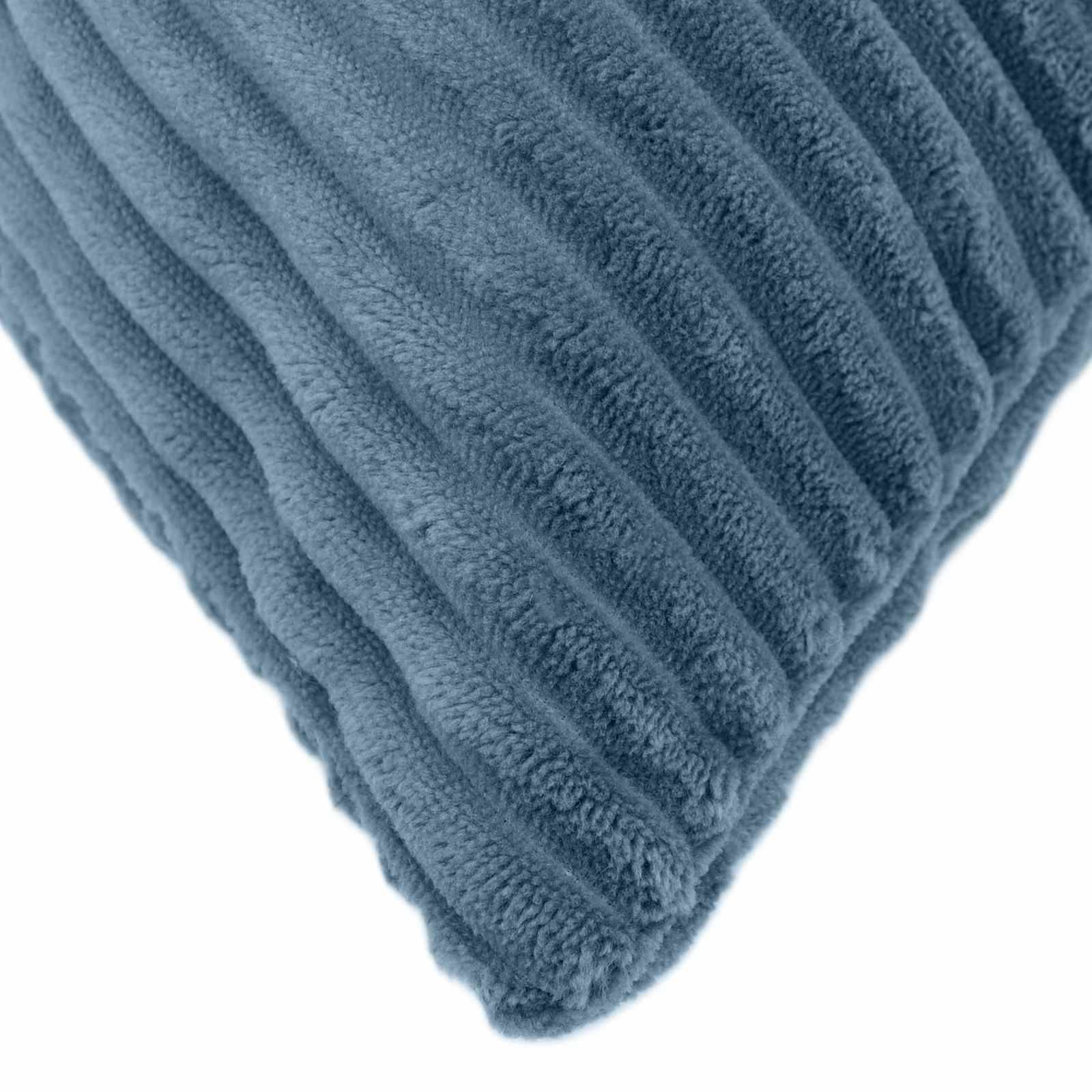 Nahaufnahme einer blauen gerippten Plüschkissencke auf weißem Hintergrund.