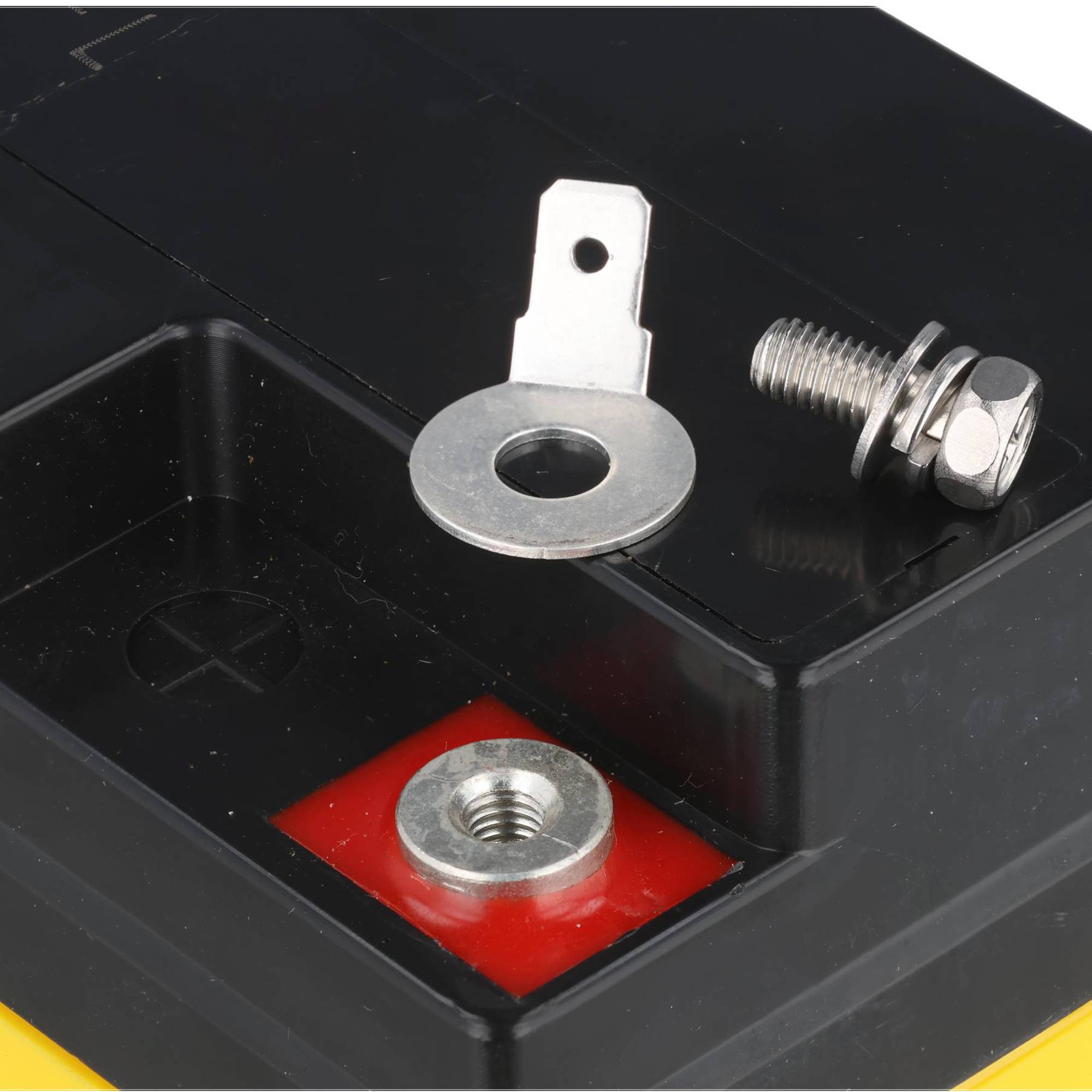 Nahaufnahme eines Batteriepolklemme mit einer Metallöse, einem Bolzen, einer Mutter und einem Gewindebolzen in einem schwarzen Gehäuse, die Verbindungshardware zeigt.