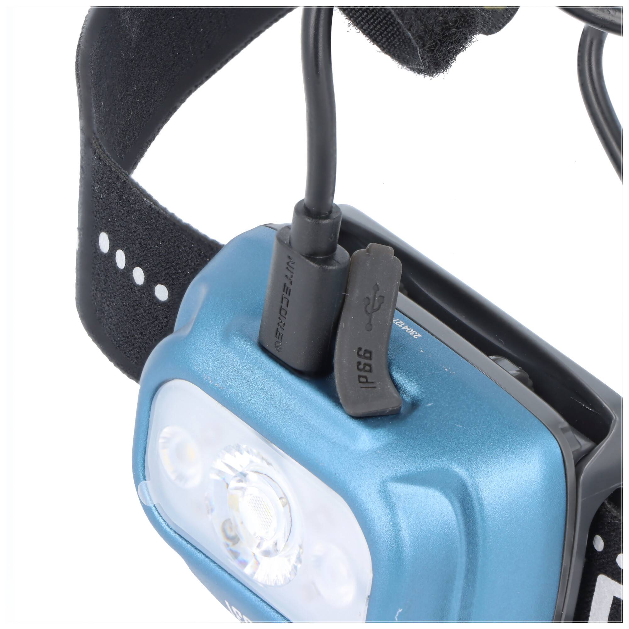 Nahaufnahme einer blauen Stirnlampe mit verstellbarem schwarzen Riemen und angeschlossenem Ladekabel oben.
