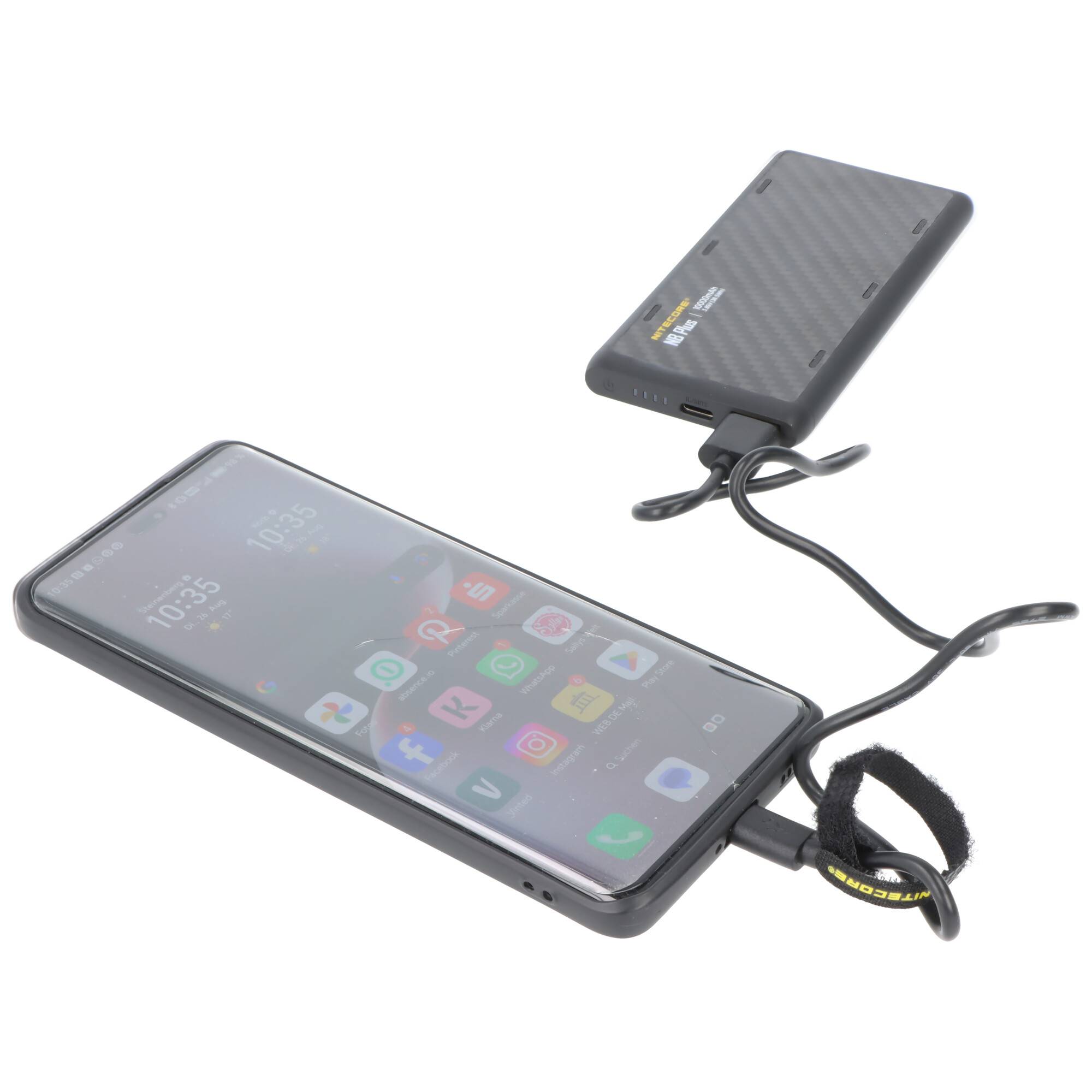 Smartphone, das über ein Kabel mit einer tragbaren Powerbank verbunden ist, was das mobile Laden unterwegs veranschaulicht.