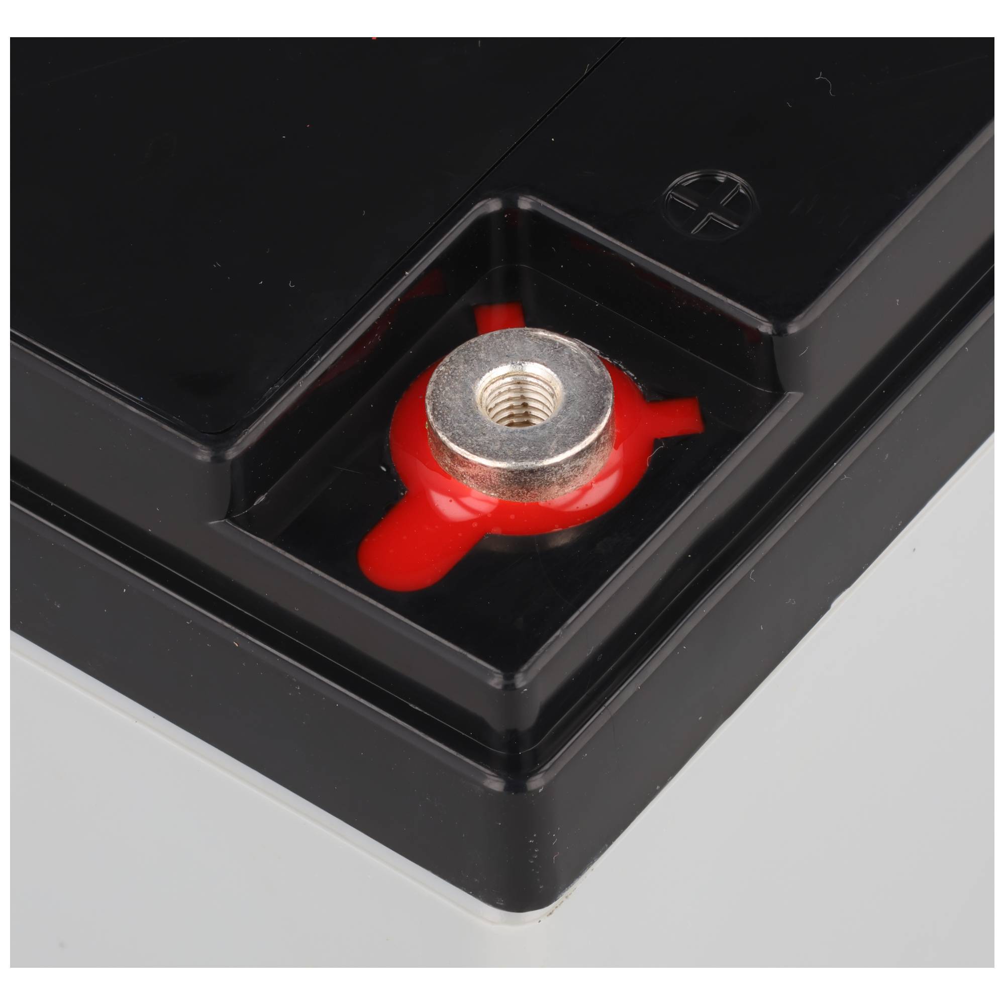 Nahaufnahme eines schwarzen Batteriepols mit einem roten Pluspol-Stecker und einer Gewindemetalleinsatz, die den positiven Verbindungspunkt anzeigt.