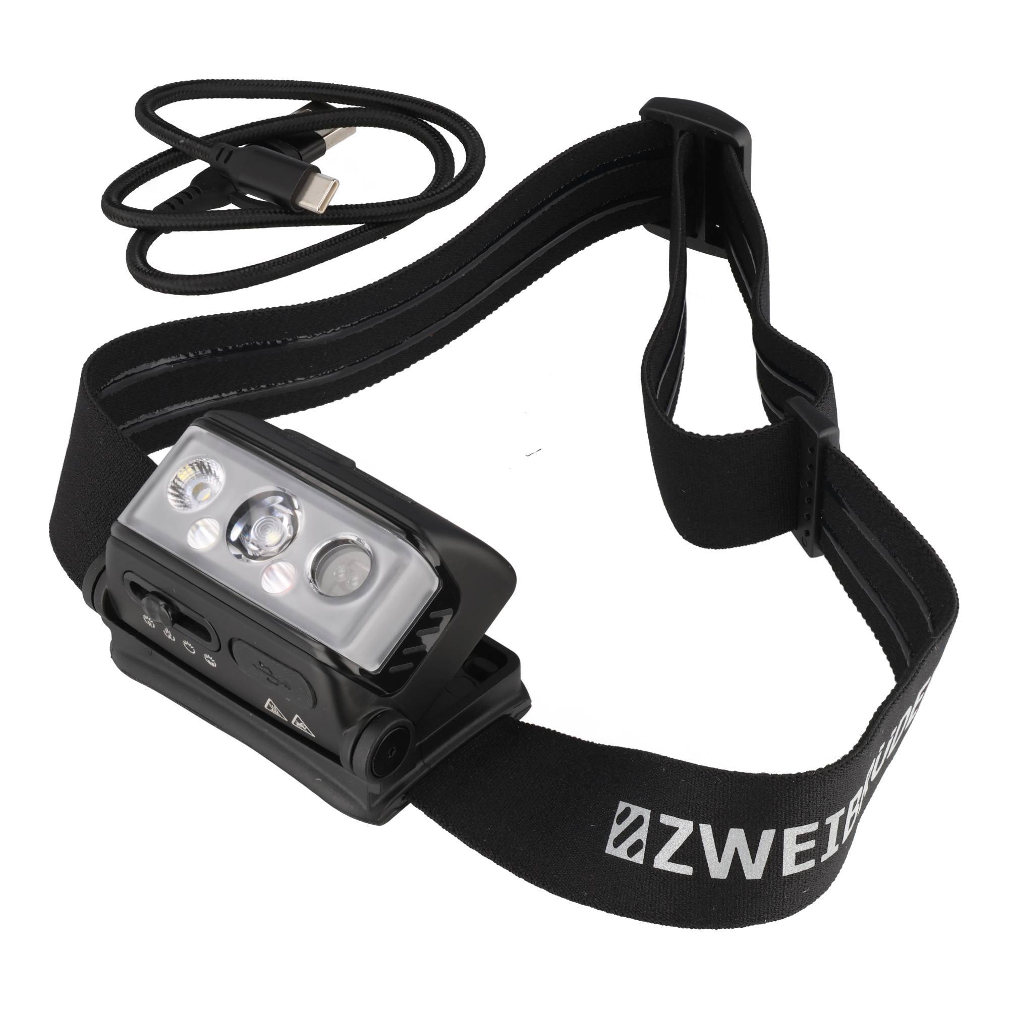 Schwarze ZWEI Stirnlampe mit verstellbarem Elastikband und USB-Ladekabel, gezeigt auf weißem Hintergrund.