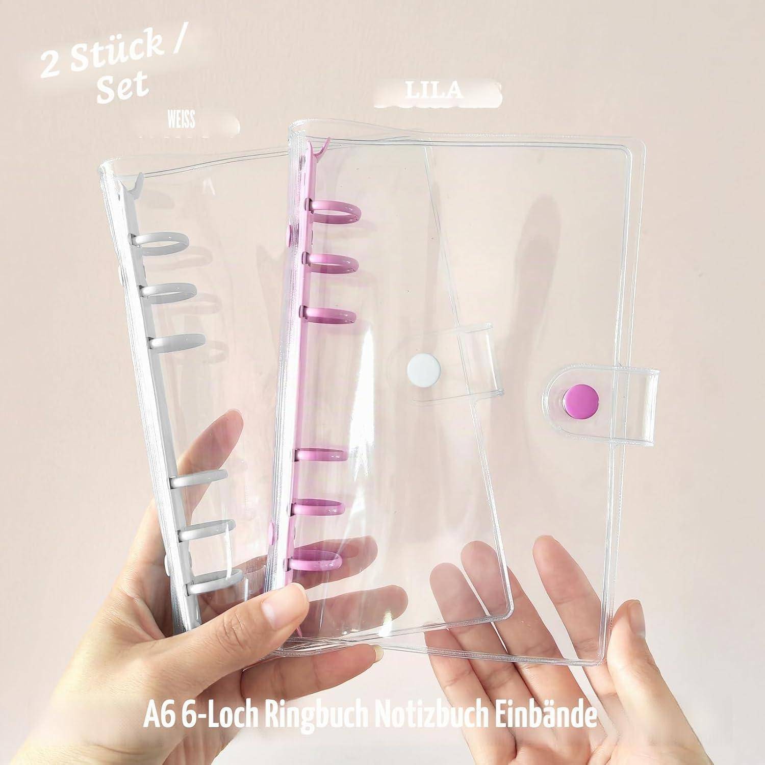 Eine Hand hält zwei durchsichtige A6 6-Ring-Notizbuch-Einbände, einen mit grauen Ringen und einen mit rosa Ringen, beschriftet mit „2 Stück/Set