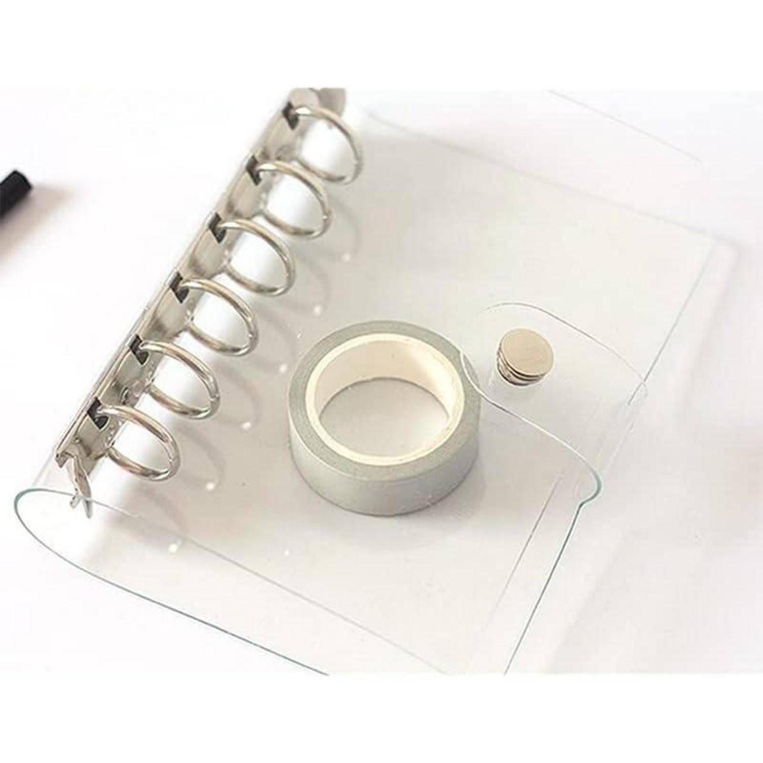 Transparente Kunststoff-Ringbinder-Notizbuchüberziehung mit einer Rolle Klebeband und einem kleinen runden Knopf auf weißem Hintergrund.