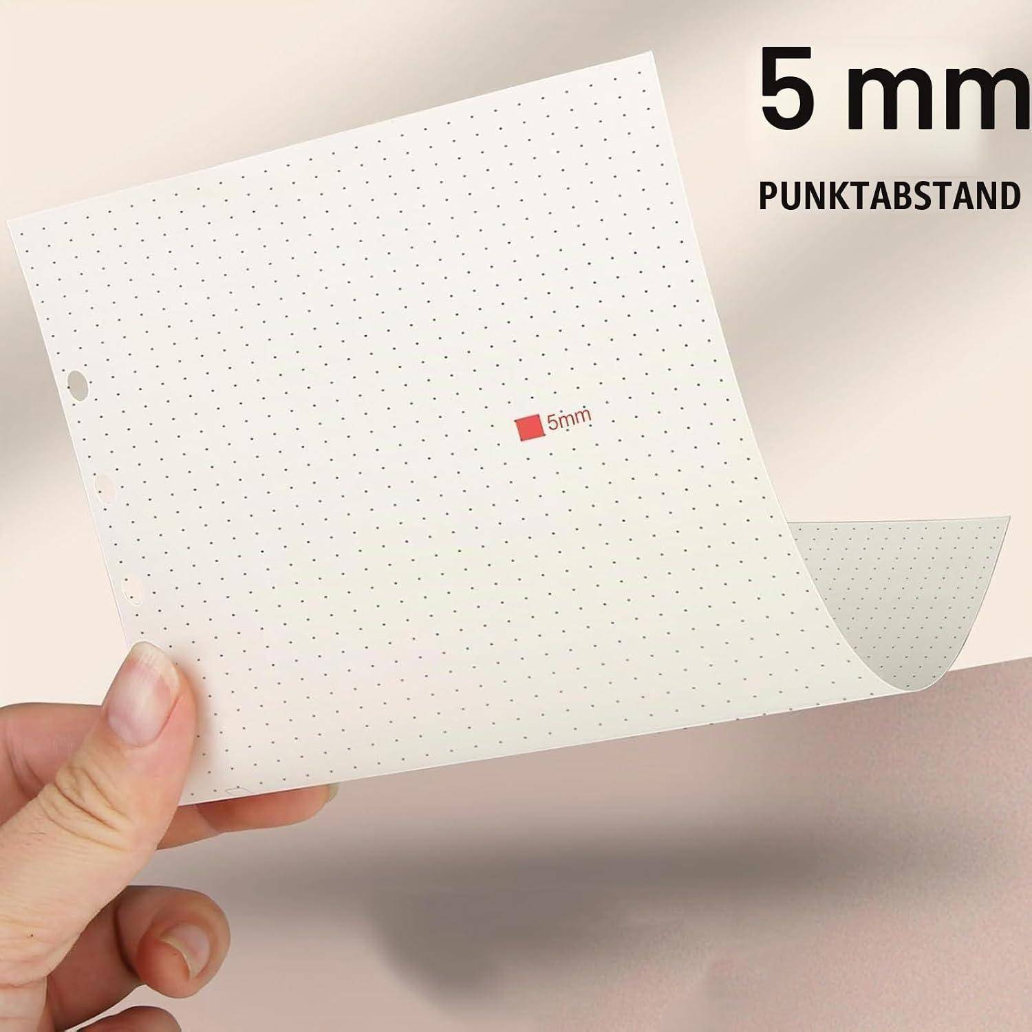Hand hält ein Blatt Papier mit 5-mm-Punktraster, beschriftet mit „5mm Punktabstand