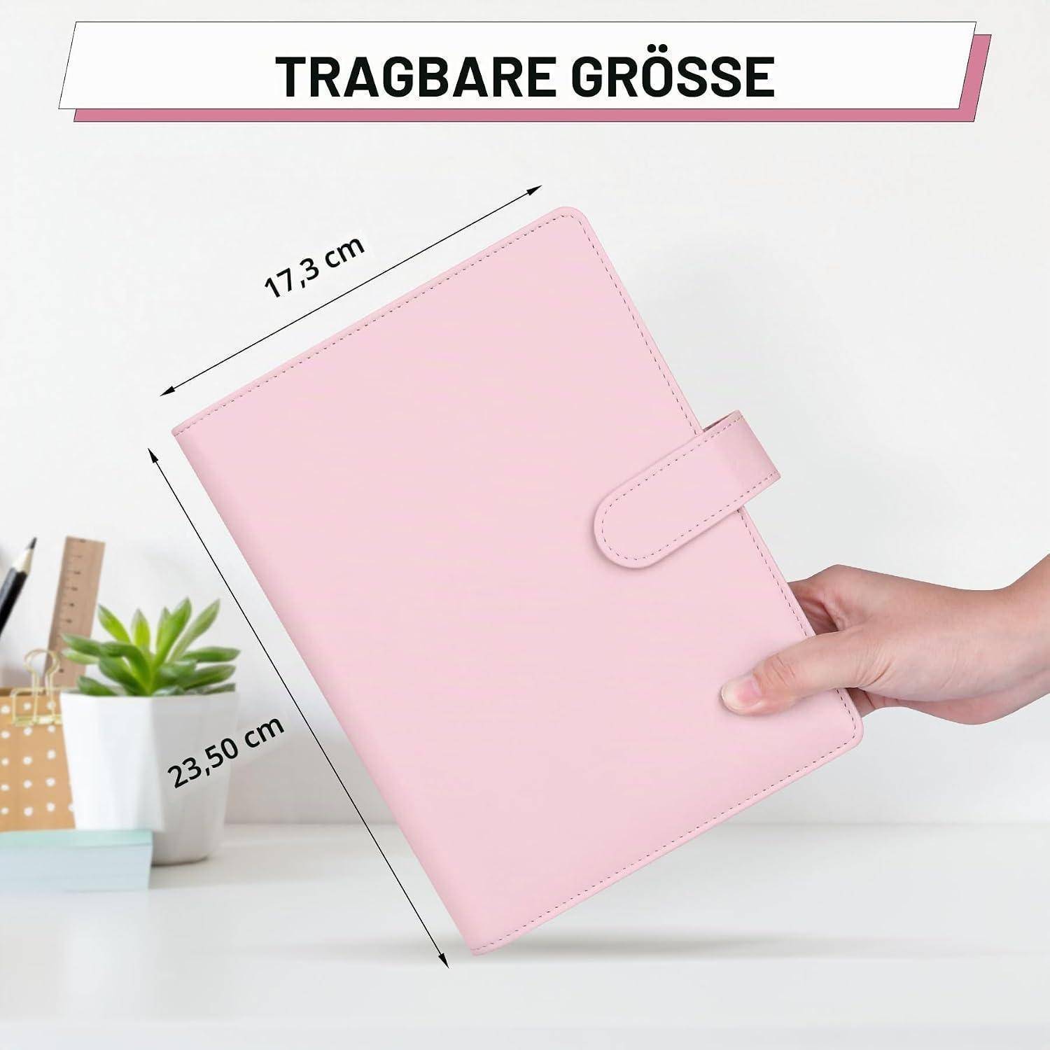 Rosafarbenes Notizbuch-Planer in einer Hand gehalten, gekennzeichnet mit „TRAGBARE GRÖSSE