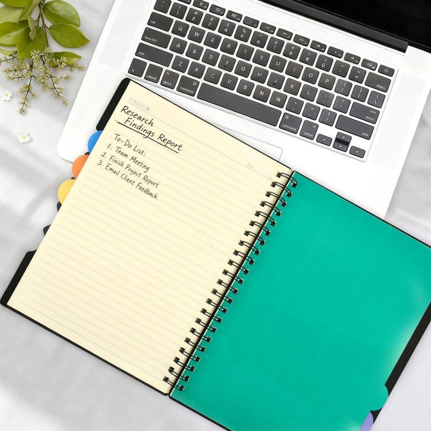 Offenes Notizbuch neben einem Laptop, mit einer handschriftlichen Forschungsergebnisse-Bericht-To-Do-Liste auf der linken Seite und einer leeren türkisfarbenen Seite auf der rechten Seite.