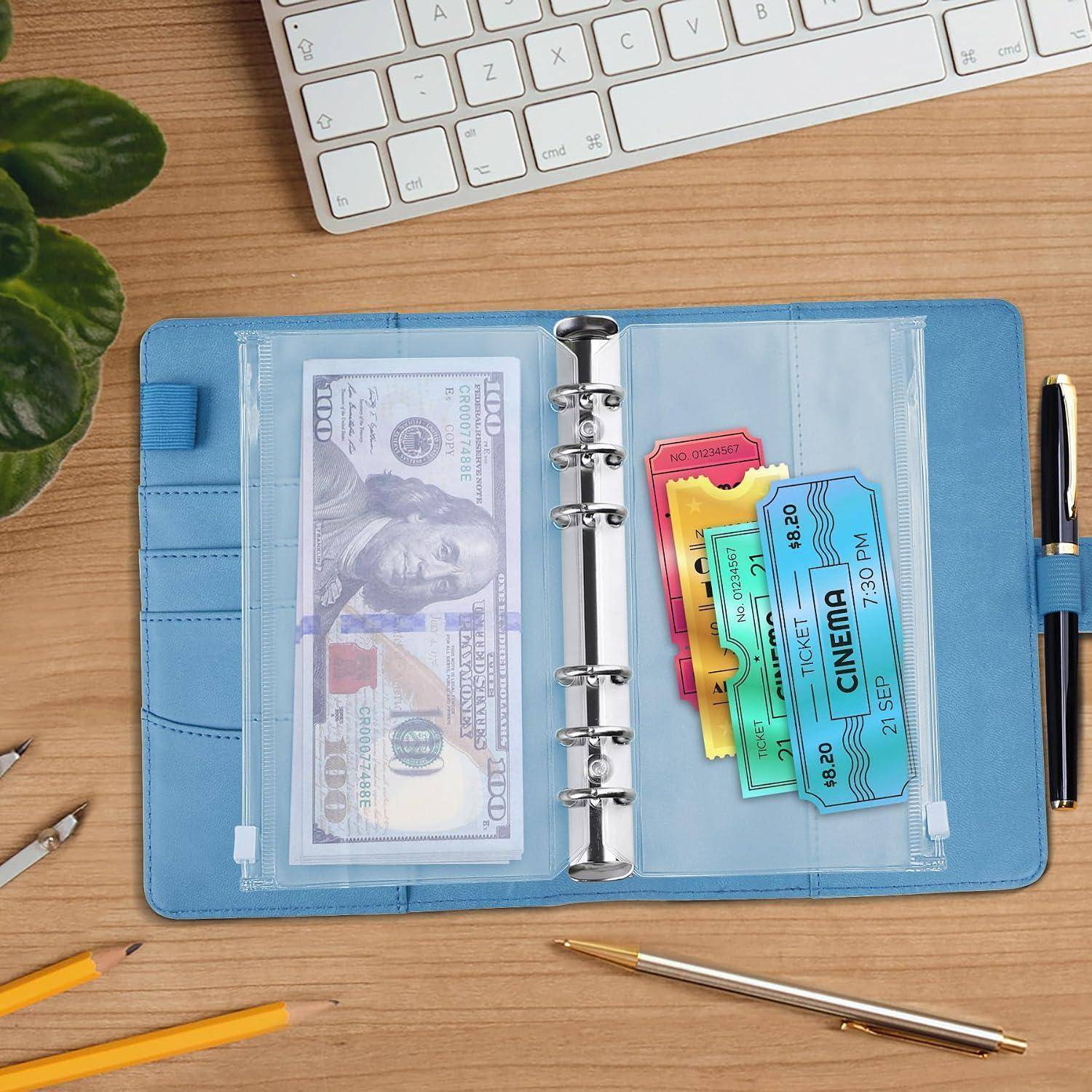 Blauer Ordnergeldbeutel mit Bargeld in einer Tasche und bunten Kinokarten in der anderen Tasche auf einem Holzschreibtisch neben einer Tastatur und Stiften.