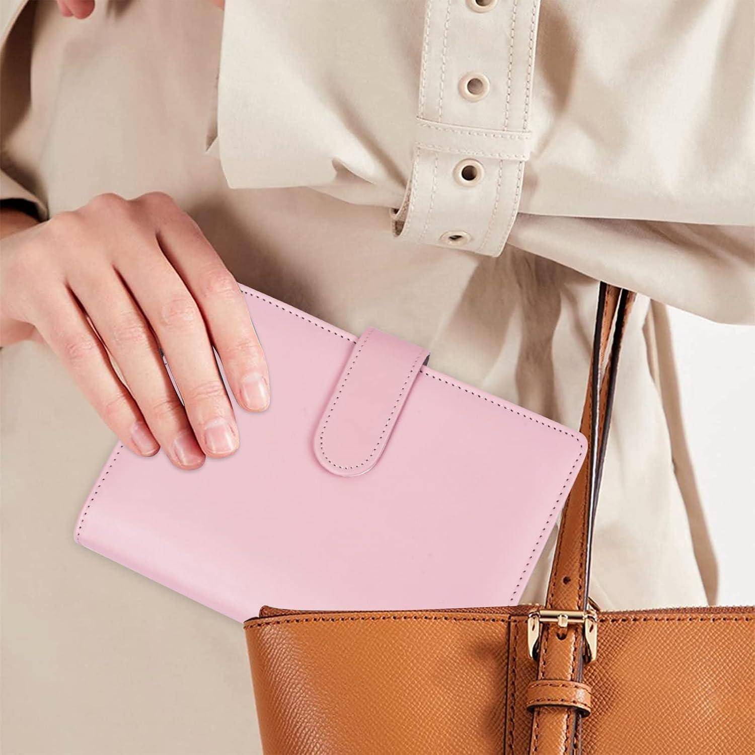 Person, die eine rosa Geldbörse über einer beigen Handtasche hält, zeigt eine Mode-Accessoires-Nahaufnahme.