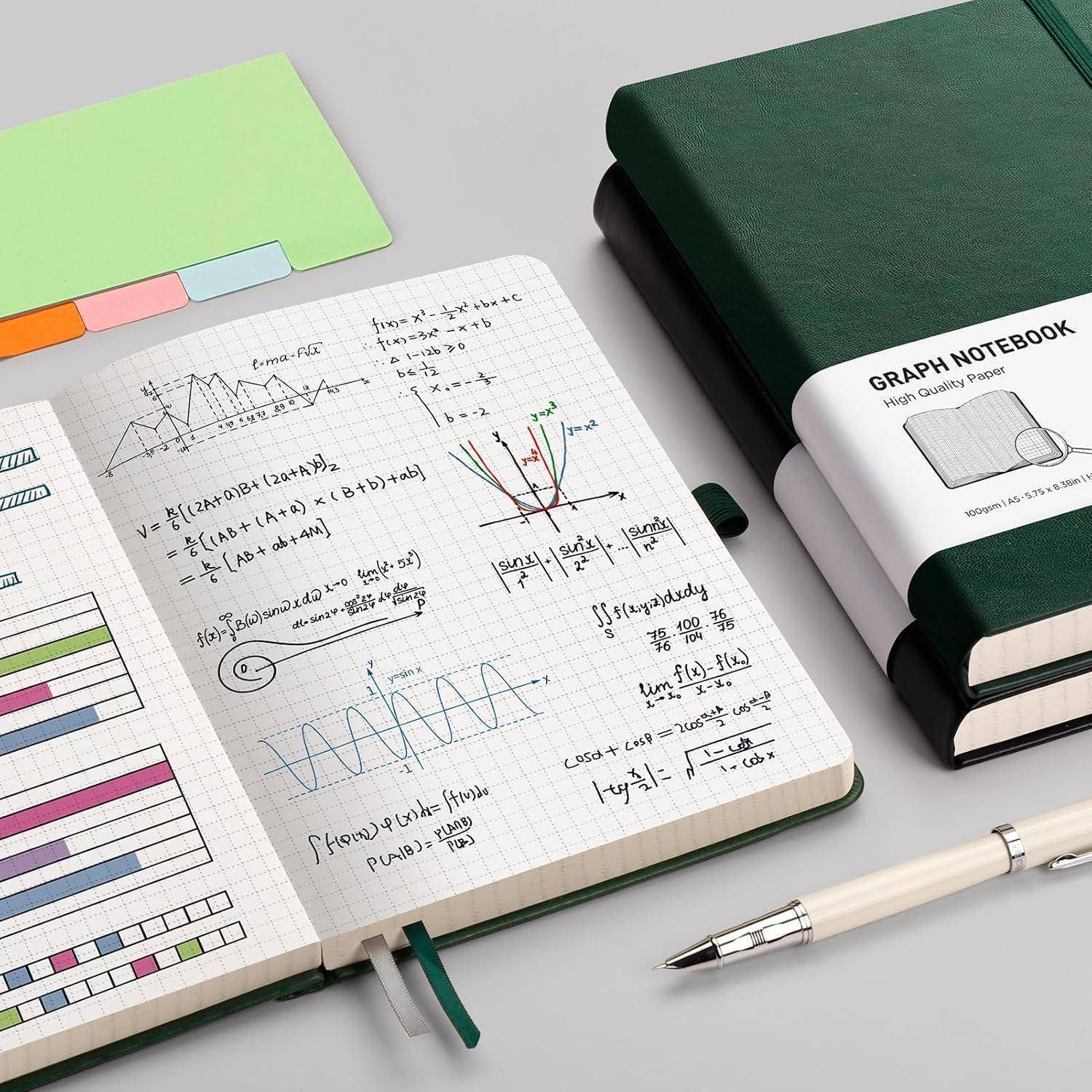 Offenes Notizbuch mit handgeschriebenen mathematischen Formeln, Diagrammen, Klebetabs und einem Stift neben einem geschlossenen grünen Notizbuch mit der Aufschrift „GRAPH NOTEBOOK