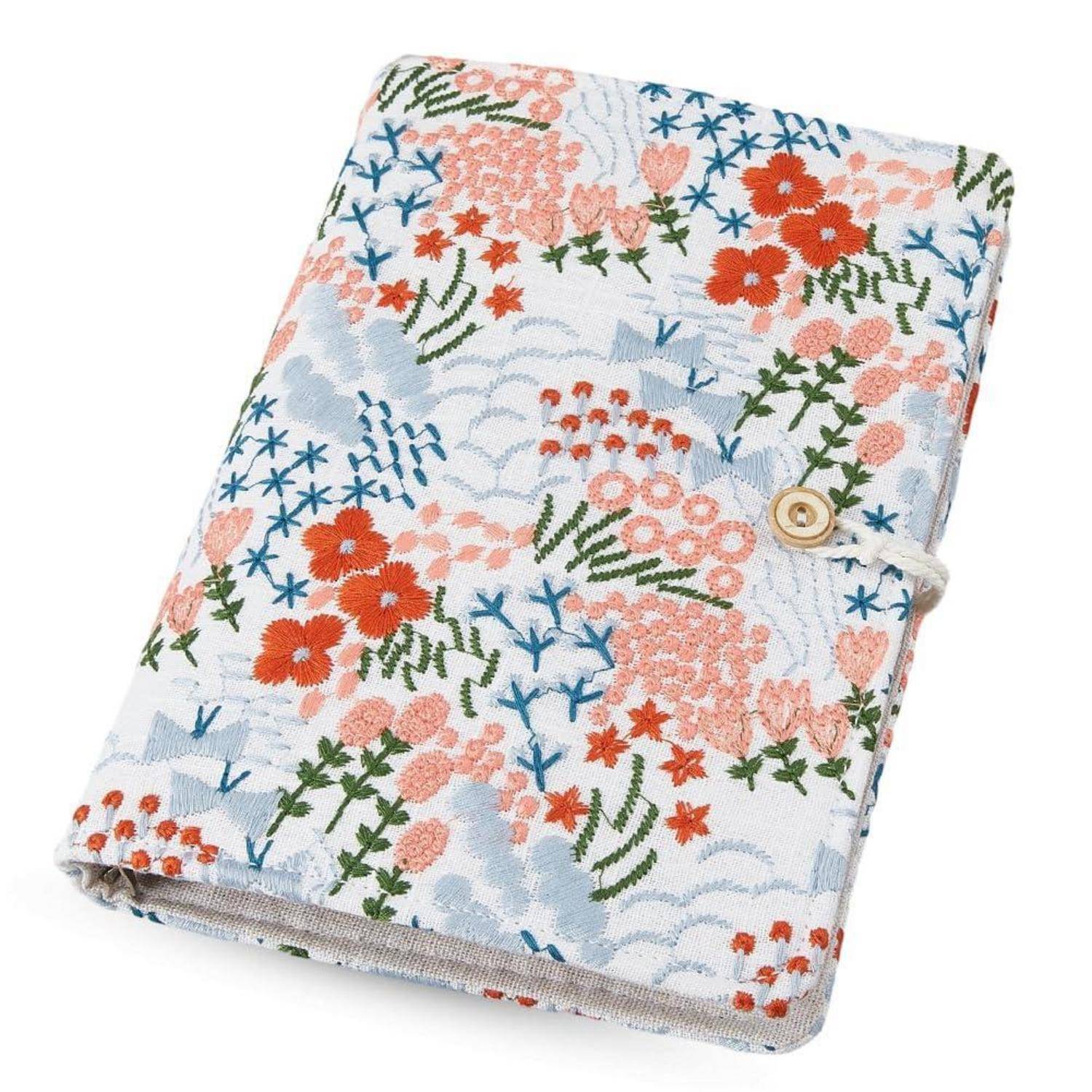 Notizbucheinband mit Blumenmuster und Knopf-Schlaufen-Verschluss auf weißem Hintergrund.