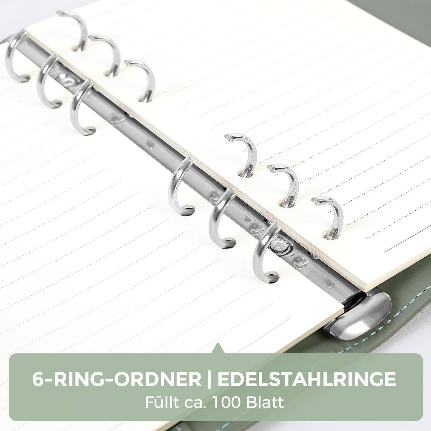 Nahaufnahme eines Sechsring-Ordners mit Metallringen und linierten Blankoblättern; das Etikett besagt „6-RING-ORDNER | EDELSTAHLRINGE