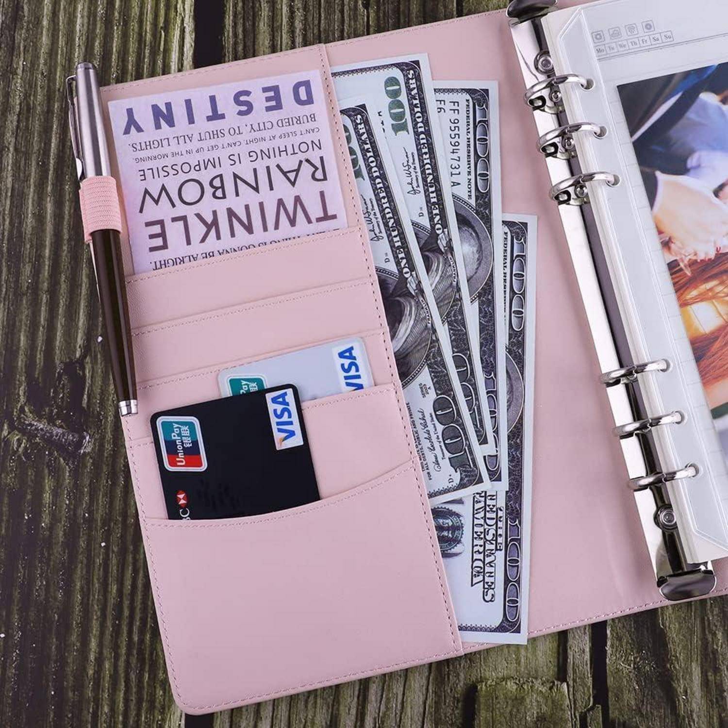 Rosa Brieftasche-Planer offen mit US-Dollar-Banknoten, Visa-Karten und einer sichtbaren Karte mit der Aufschrift „Think Like a Boss