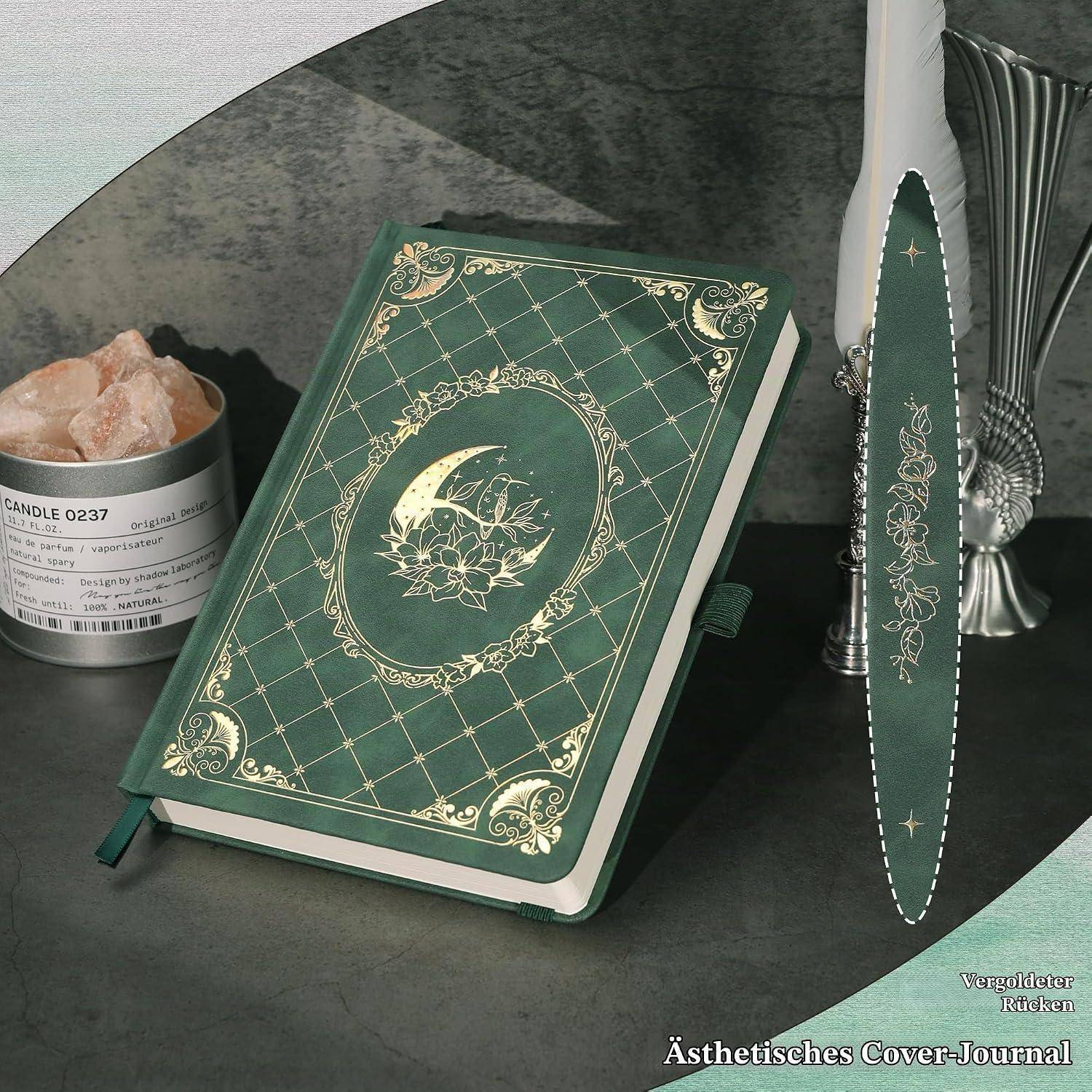 Grünes Hardcover-Tagebuch mit verziertem goldenem Halbmond auf dem Einband, gezeigt mit passendem Lesezeichen und Kerzen-Display.