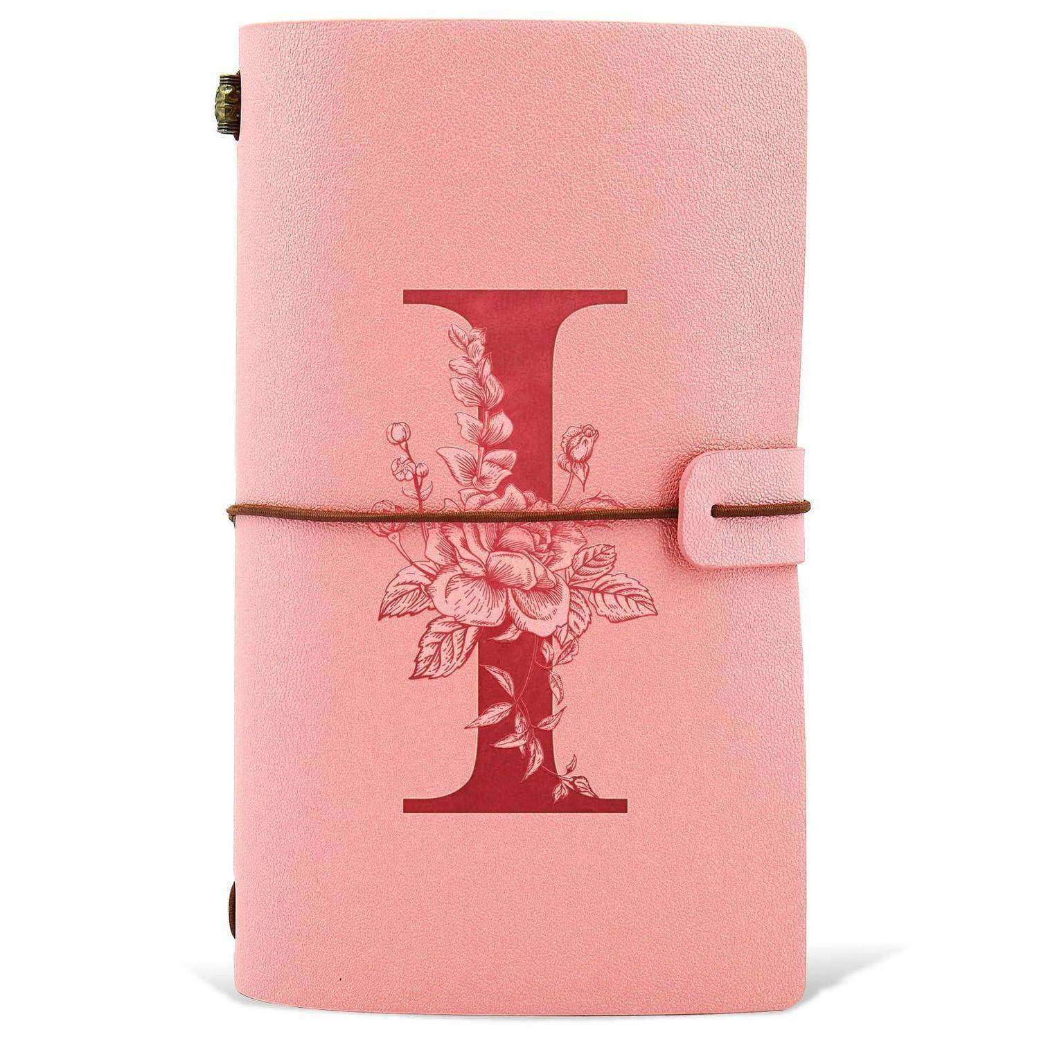Rosa Lederjournal-Notizbuch mit geprägtem Blumenmotiv und Buchstabe I auf dem Umschlag, gesichert durch ein umlaufendes Gummiband.