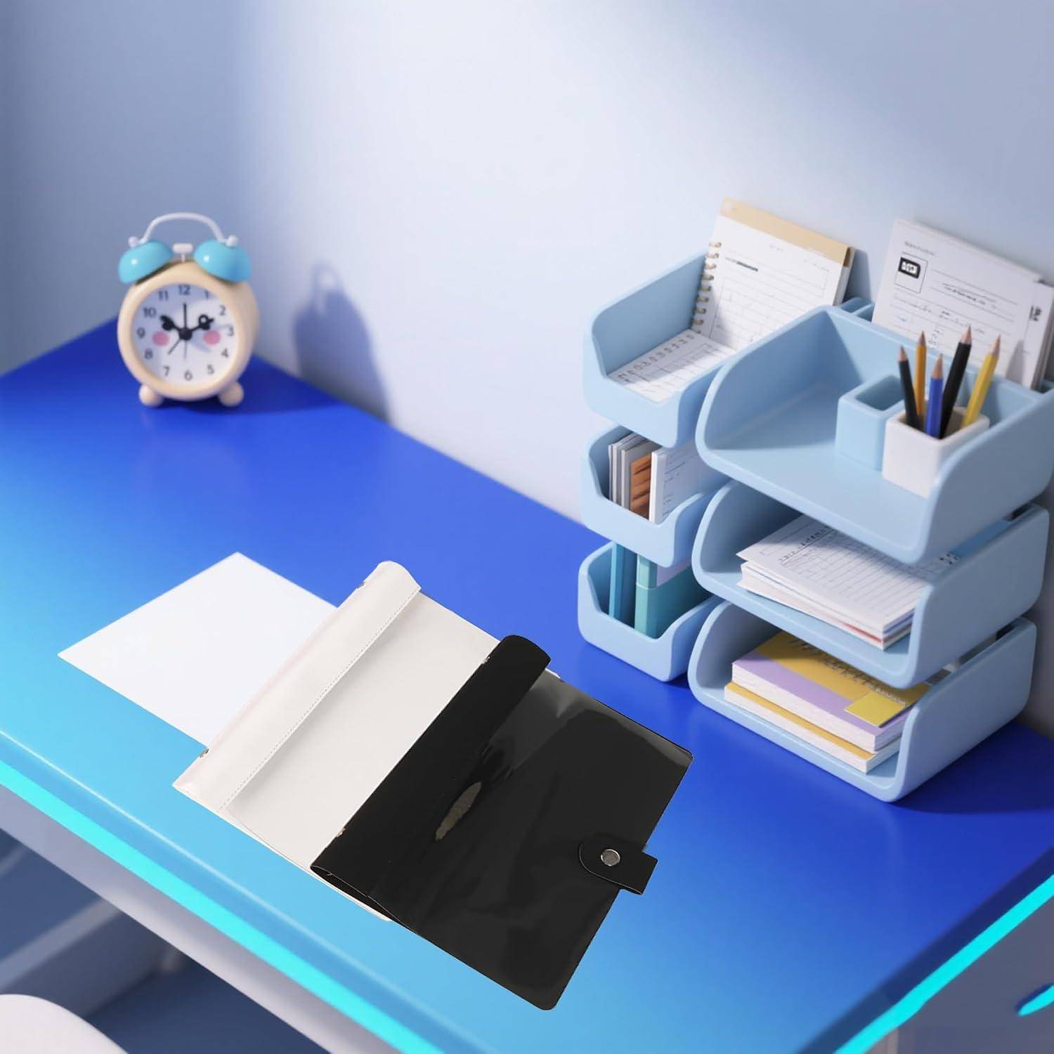 Offene schwarze Dokumententasche auf einem blauen Schreibtisch neben einer Uhr und gestapelten Büroorganizern mit Papieren, Stiften und Notizbüchern.