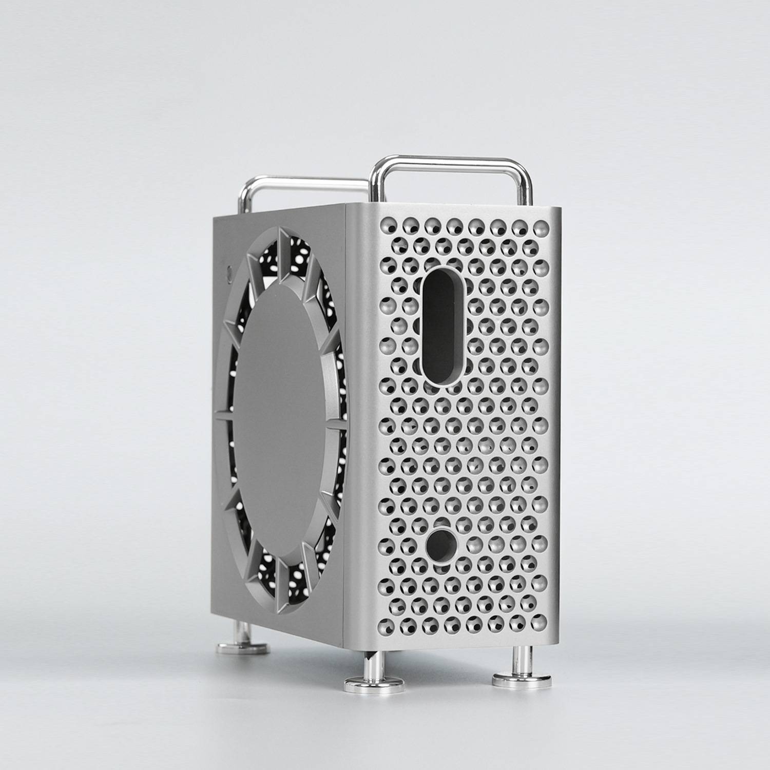 Eine kompakte Silbermetallbox mit perforierten Seitenflächen und einer großen kreisförmigen Lüfteröffnung, gezeigt auf einem einfachen grauen Hintergrund.