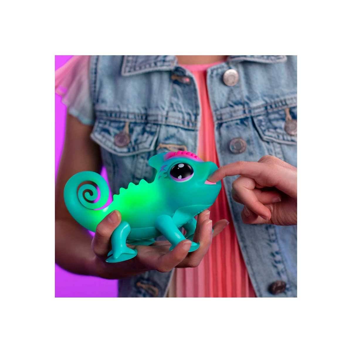 Kind hält eine leuchtende blaugrüne Spielzeugeidechse, während eine andere Hand deren Nase berührt, vor einem violetten Hintergrund und einer Jeansweste.
