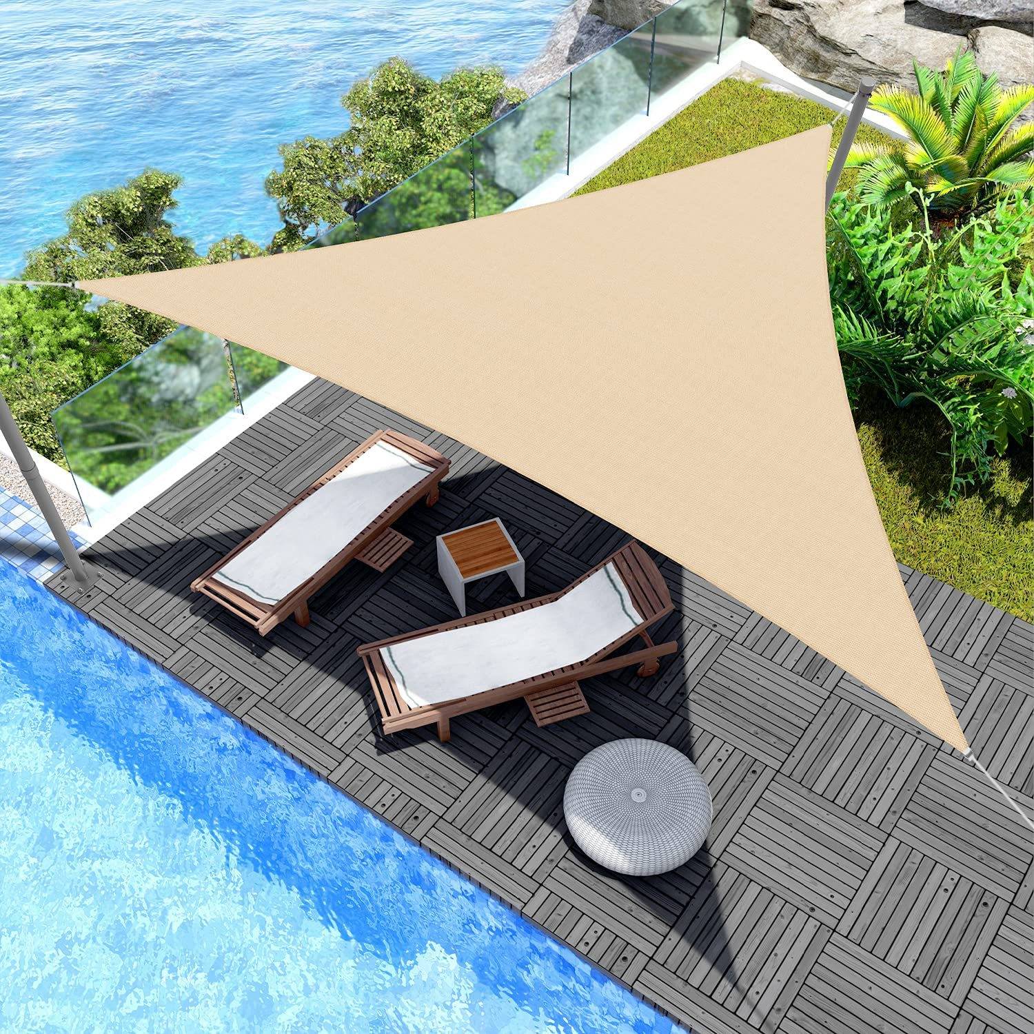 Blick von oben auf ein Pooldeck mit zwei Liegestühlen, einem kleinen Beistelltisch und einem dreieckigen Sonnensegel neben tropischer Vegetation und Wasser.