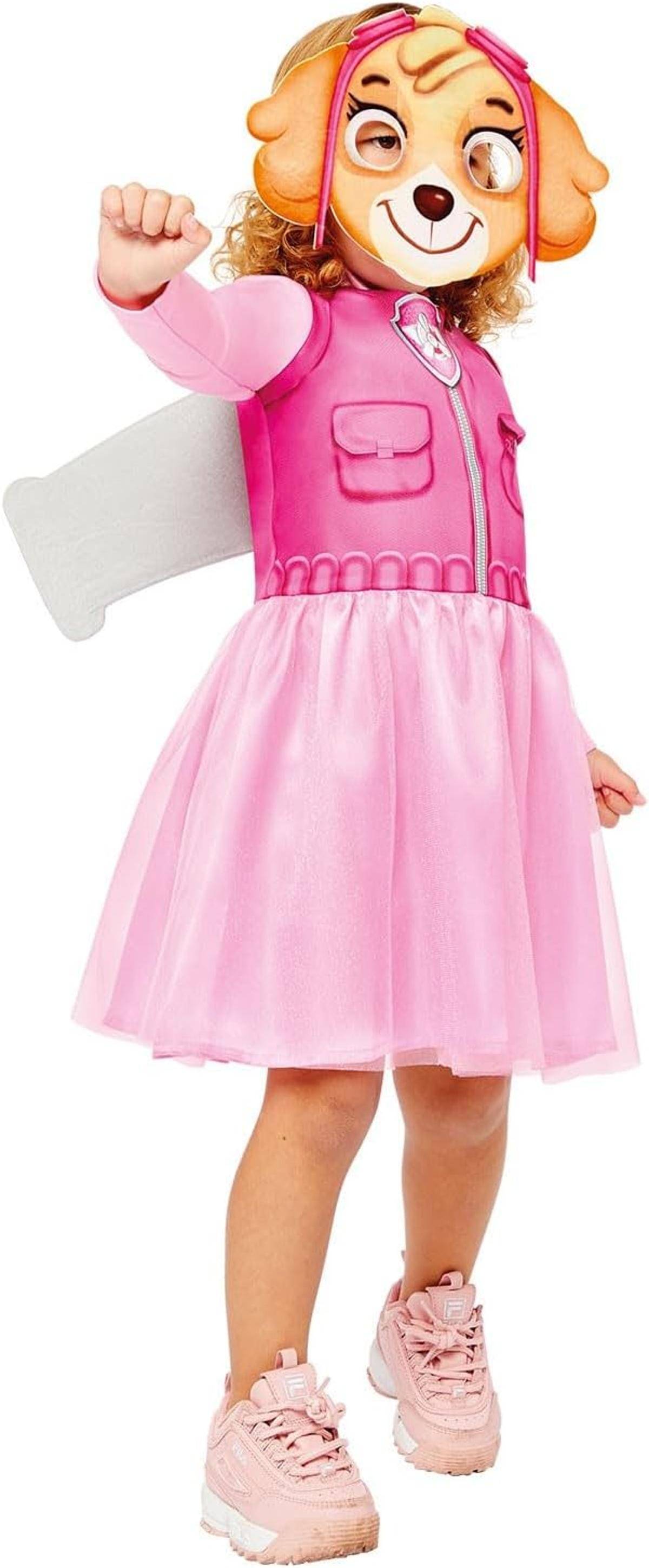 Kind in einem rosa Hundekosten-Kleid und Maske, das mit erhobener Faust und einem angehobenen Bein gegen einen weißen Hintergrund posiert.