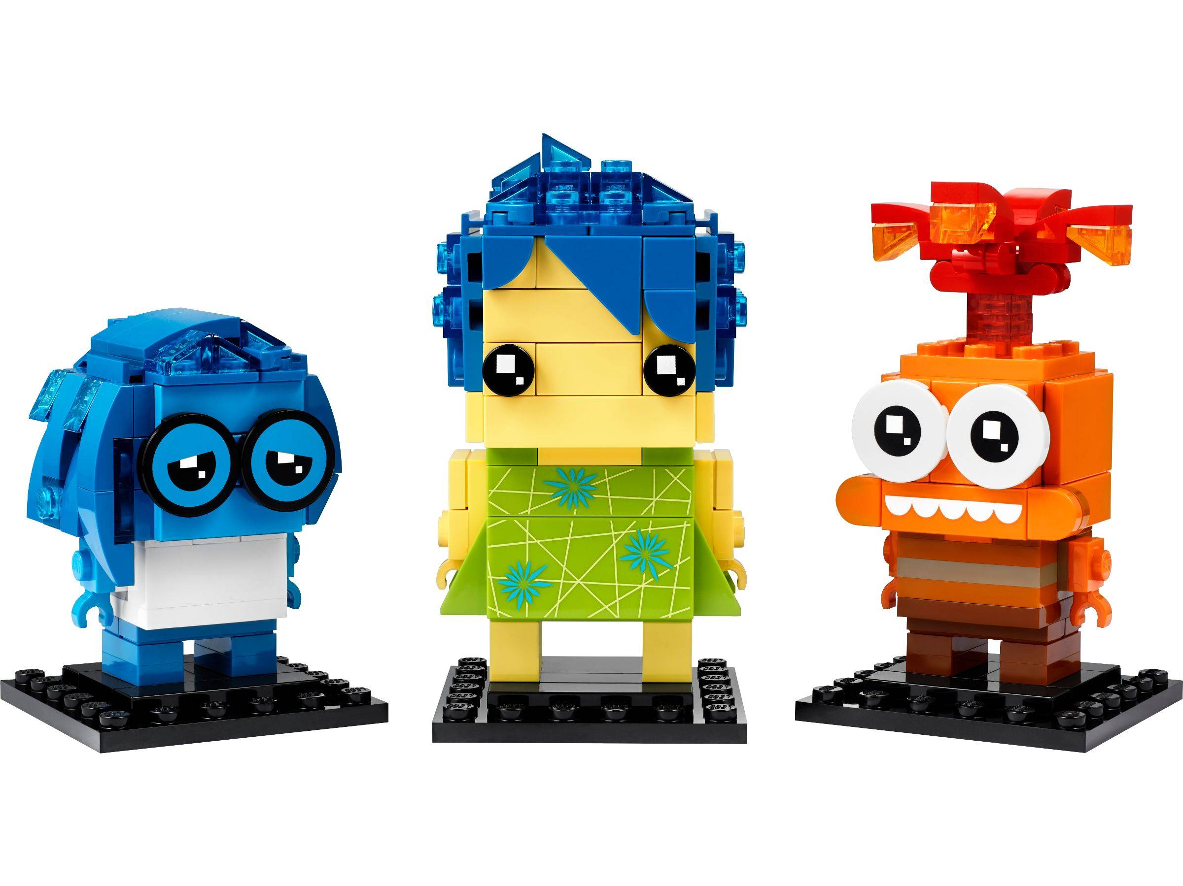 Drei LEGO-ähnliche Charakterfiguren auf schwarzen Basen: eine blaue hundeähnliche Figur, ein gelb-und-blaues Mädchen mit grünem Kleid und eine orange fuchsähnliche Figur mit großen Augen.